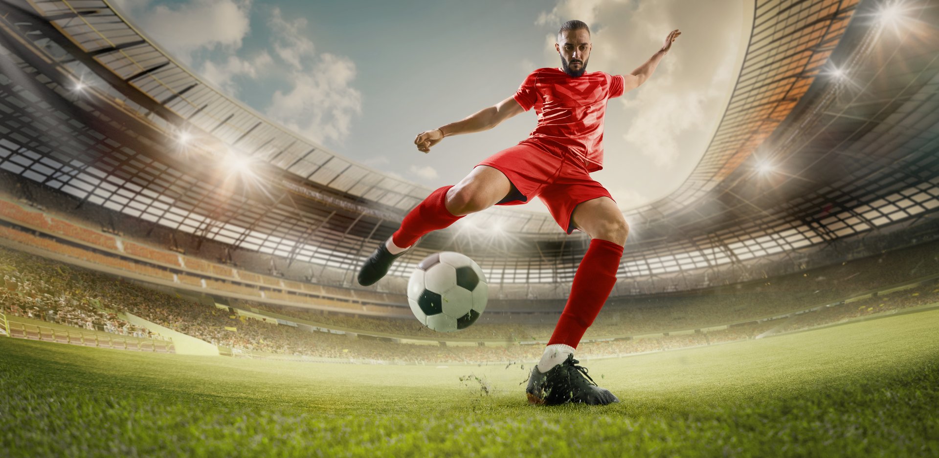 Handmade collage. Competitive football player, dressed red uniform, kicks penalty on green lush 3D rendering stadium with spectators on tribunes waiting final goal. Concept of global sport event.