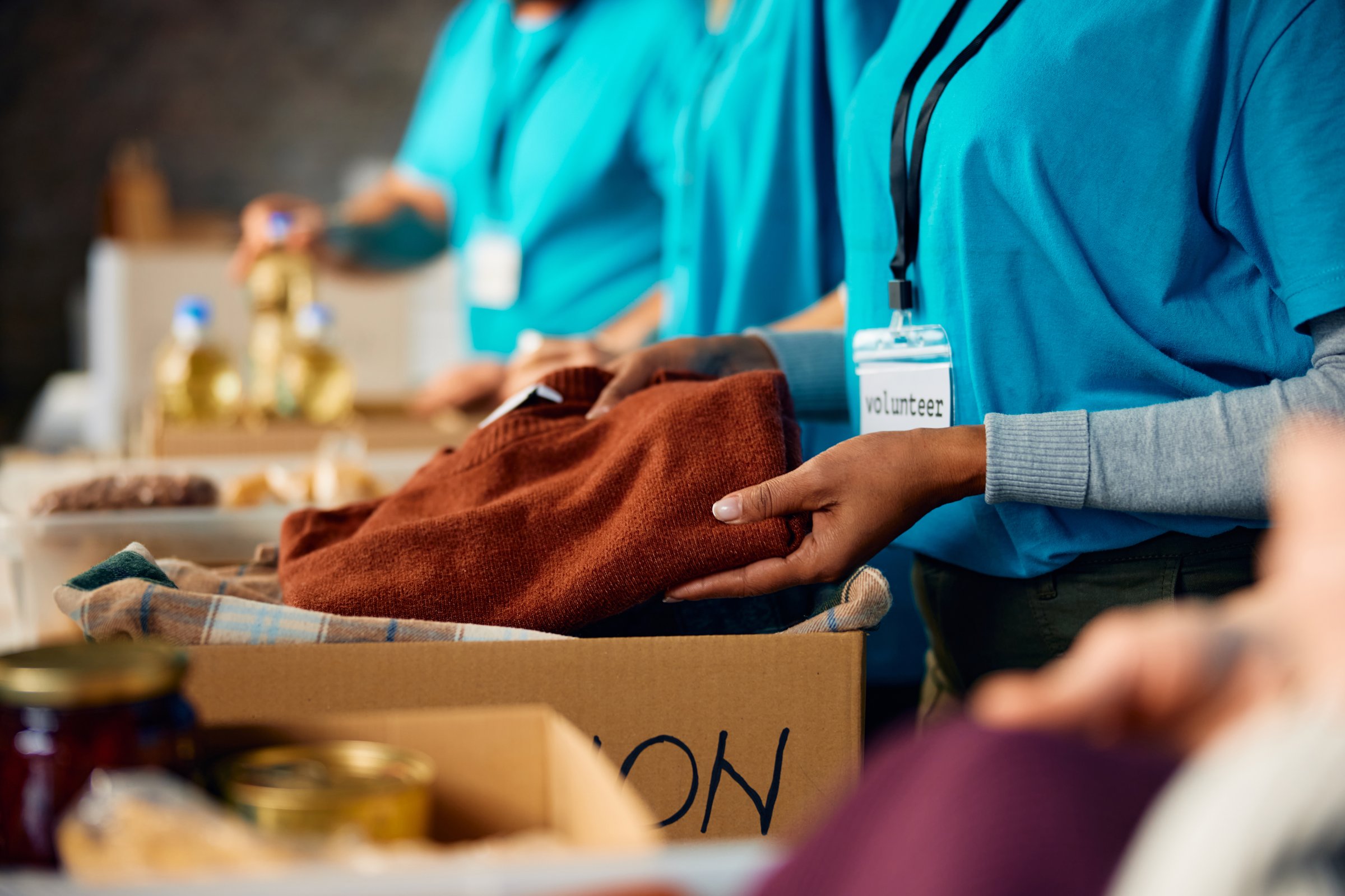 Close up of woman packing clothes into donation boxes volunteering at charitable foundation.