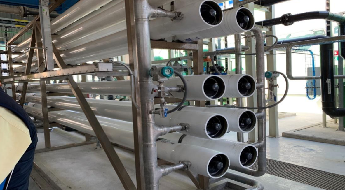 Industrial reverse osmosis water filtration system with multiple pipes and gauges in a facility.