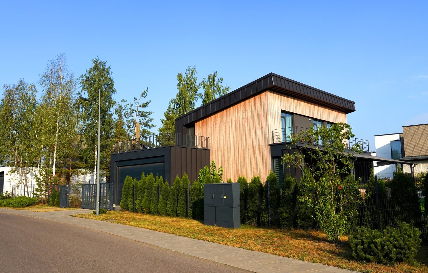 Modern luxury Villa. Street Road in Contemporary Residence. Modern Prefab house. Prefabricated home with lawn, shrubs, green courtyard in sustainable enviroment. Family House in Gated Community. Villa