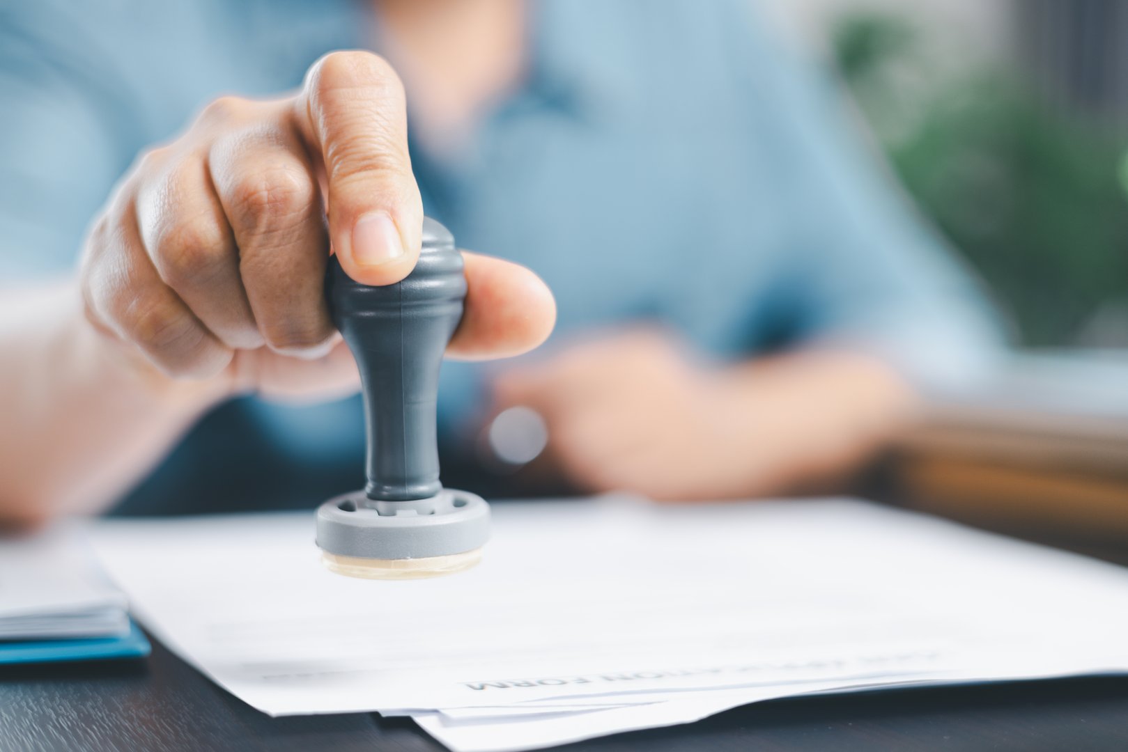 Businessman hands stamp approve on financial business approval document paper. Man hand accepted permit contract agreement. Broker manager sign contract bank guarantee approved stamp application form