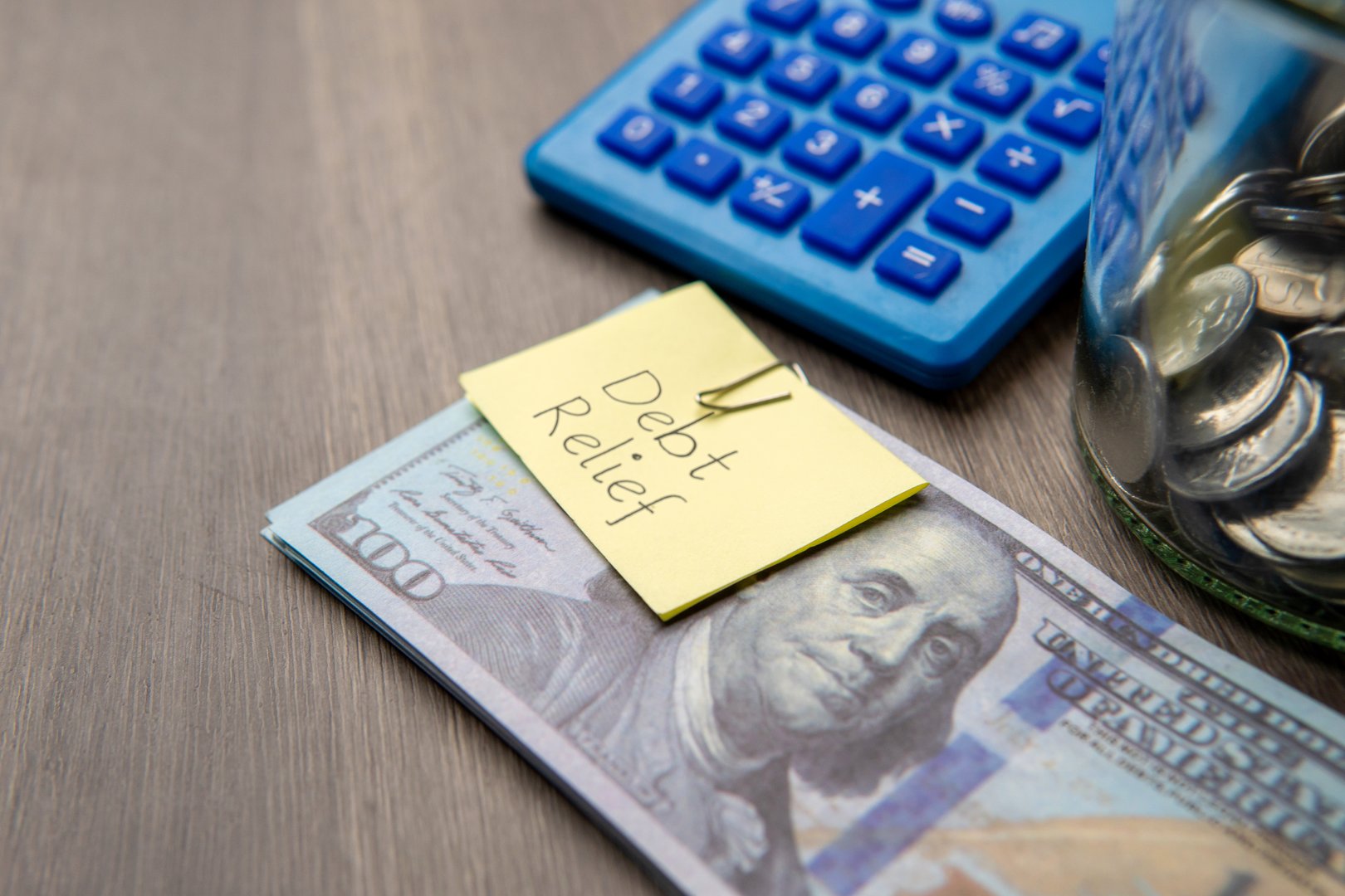 A stack of US hundred-dollar bills with a DEBT RELIEF note. Financial solutions, managing debt concept.