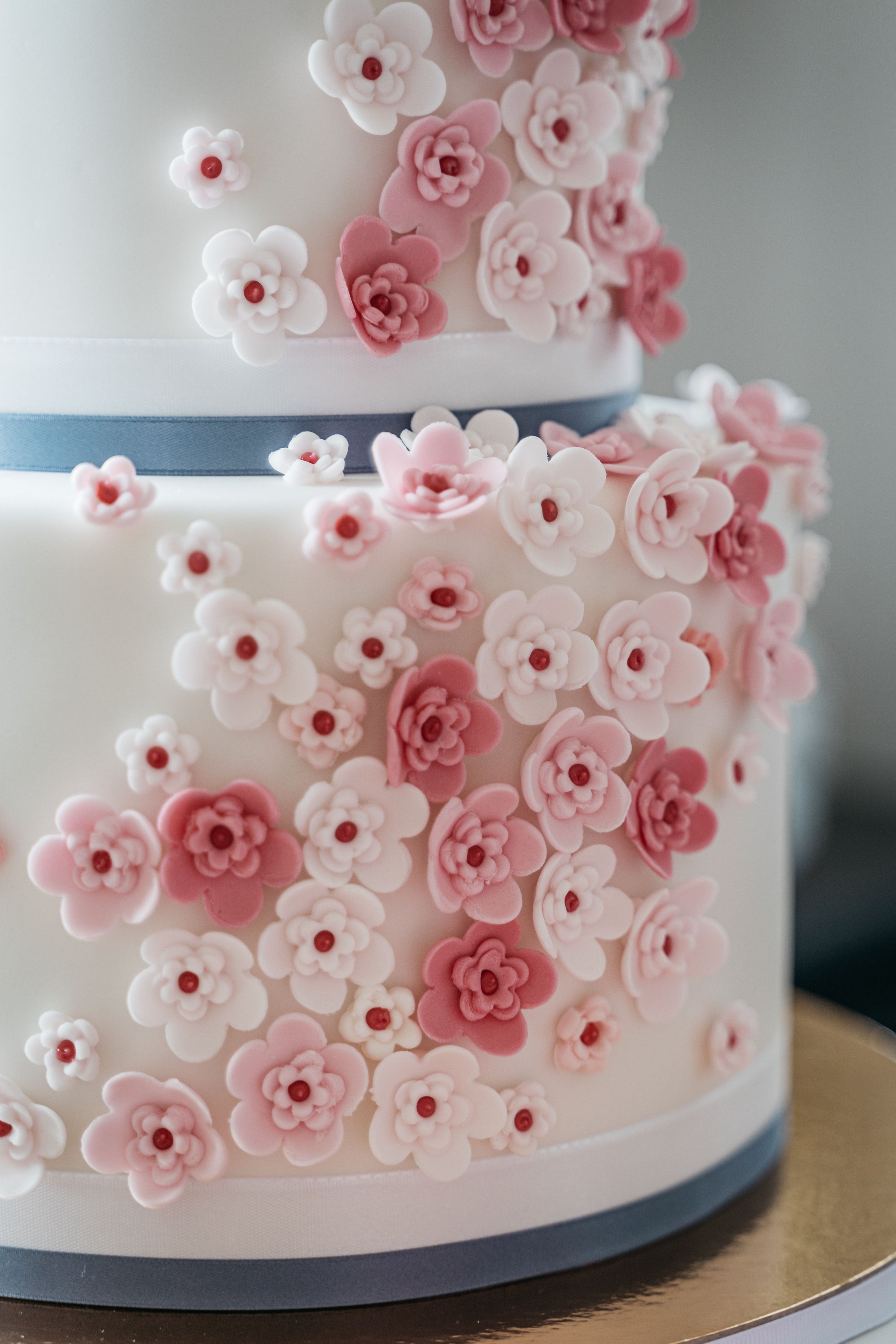 A close-up of a floral decorated wedding cake with pink and white sugar flowers on a two-tiered design.