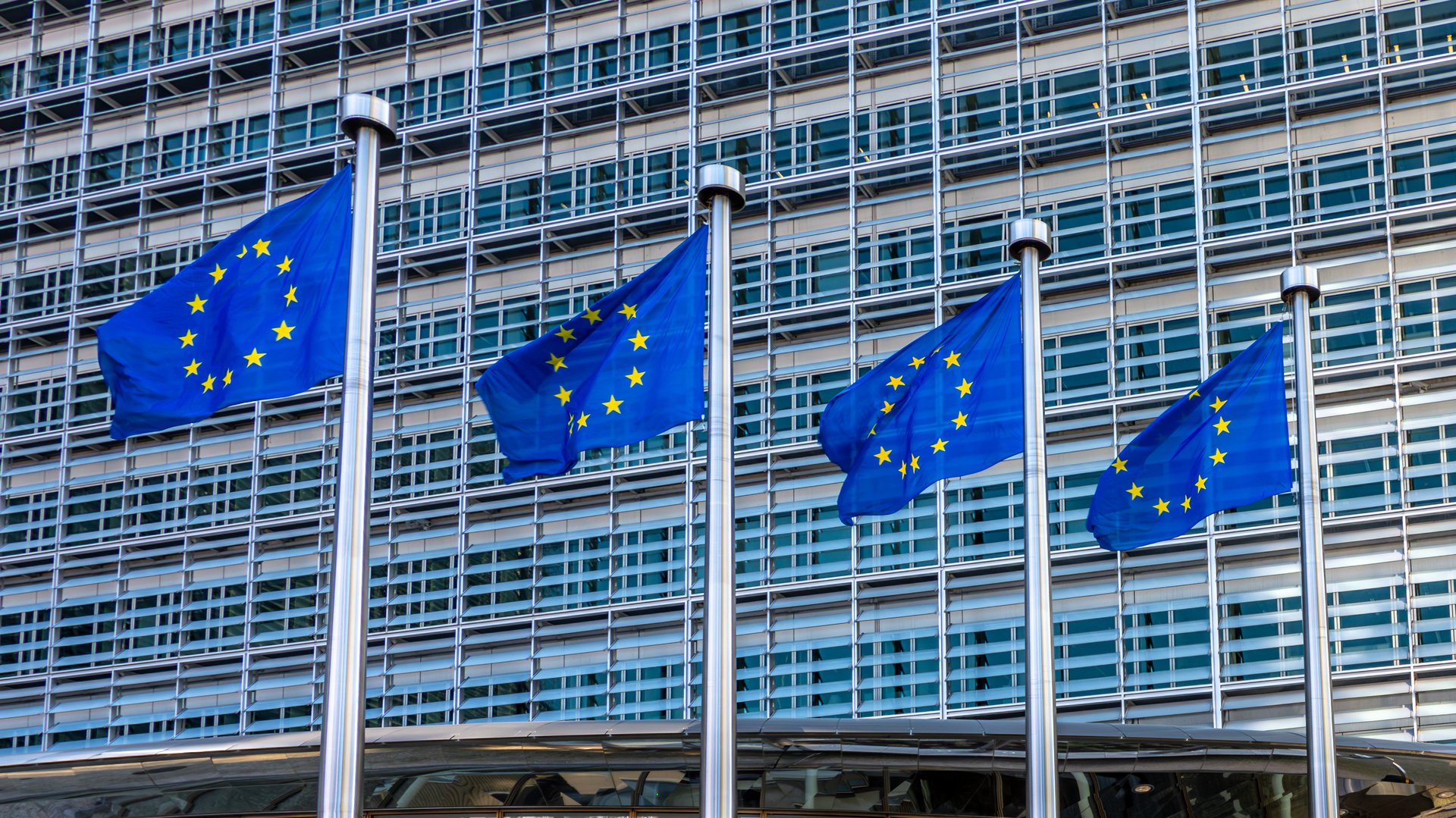 Four European flags, symbols of the European Union (EU), fluttering against the Berlaymont building, headquarters of the European Commission in Brussels, Belgium