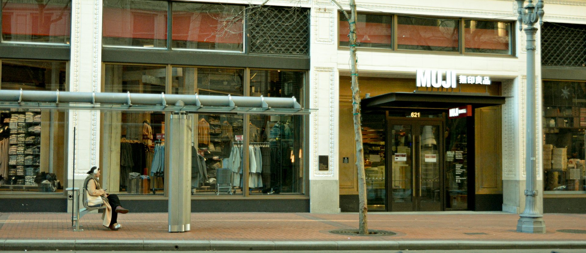Person waiting for a bus in front of Portland MUJI Store
