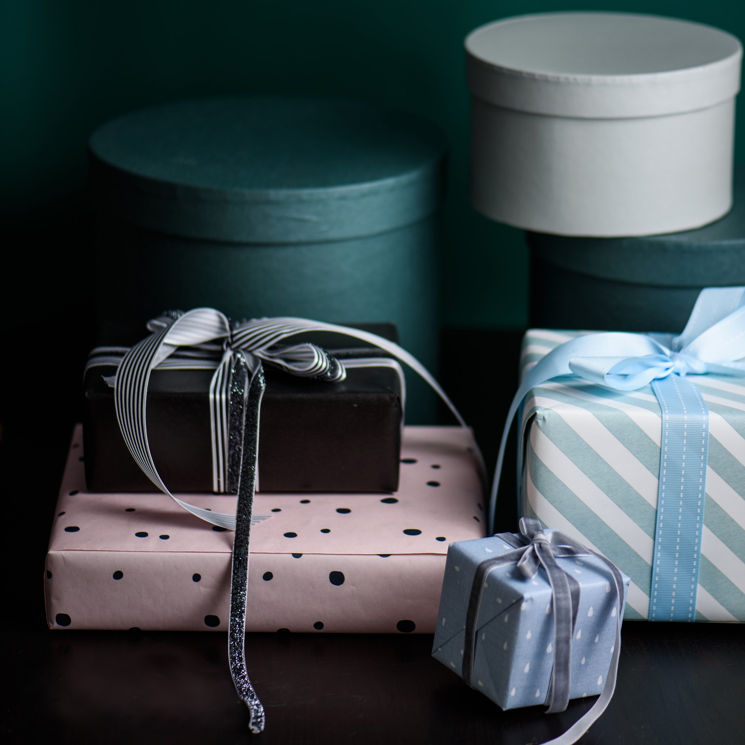 Gift box wrapped in paper with ribbon and wrapping materials on a green background