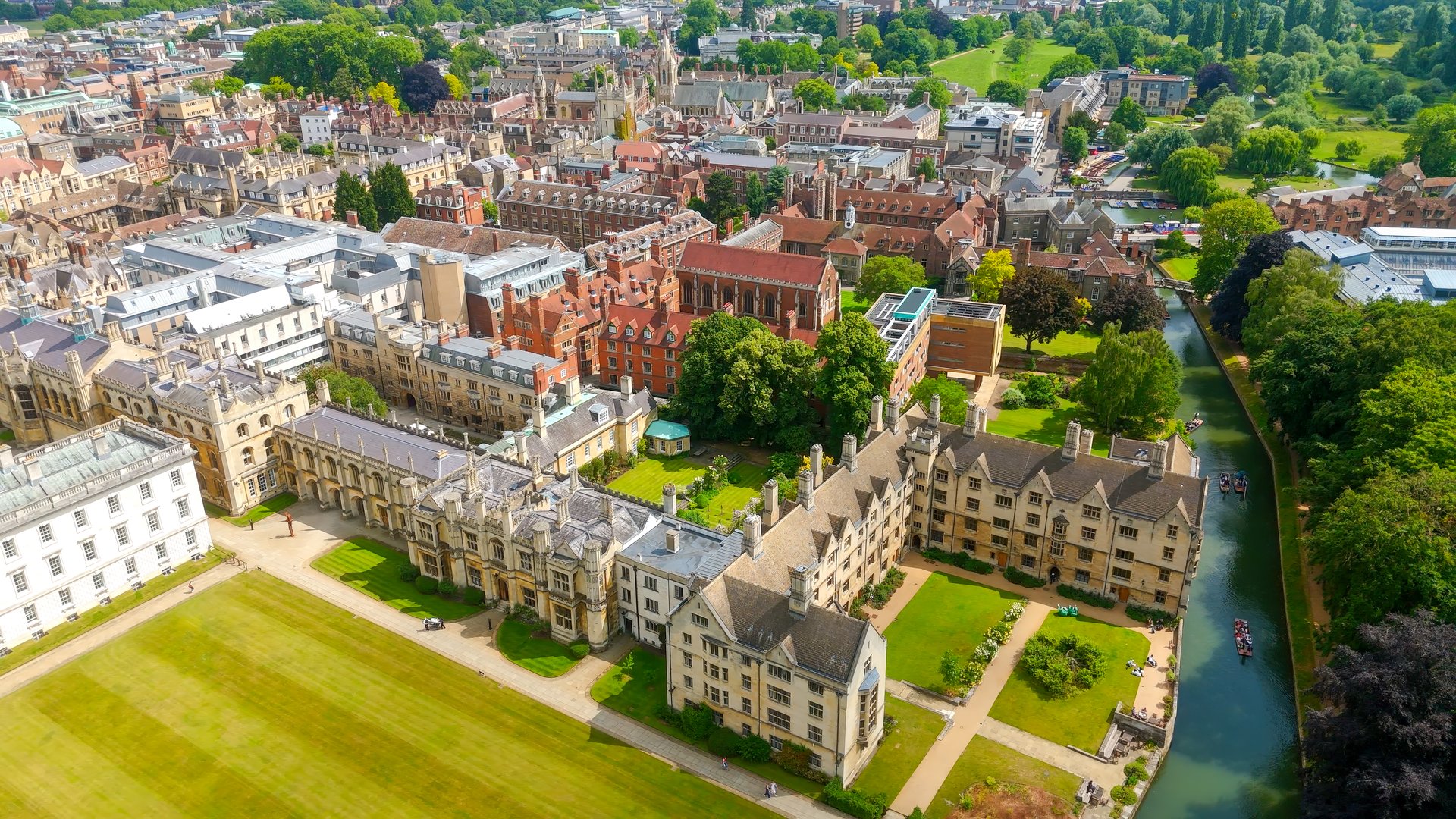 Aerial view of Cambridge University colleges, river Cam, green lawns, and trees on a sunny summer day