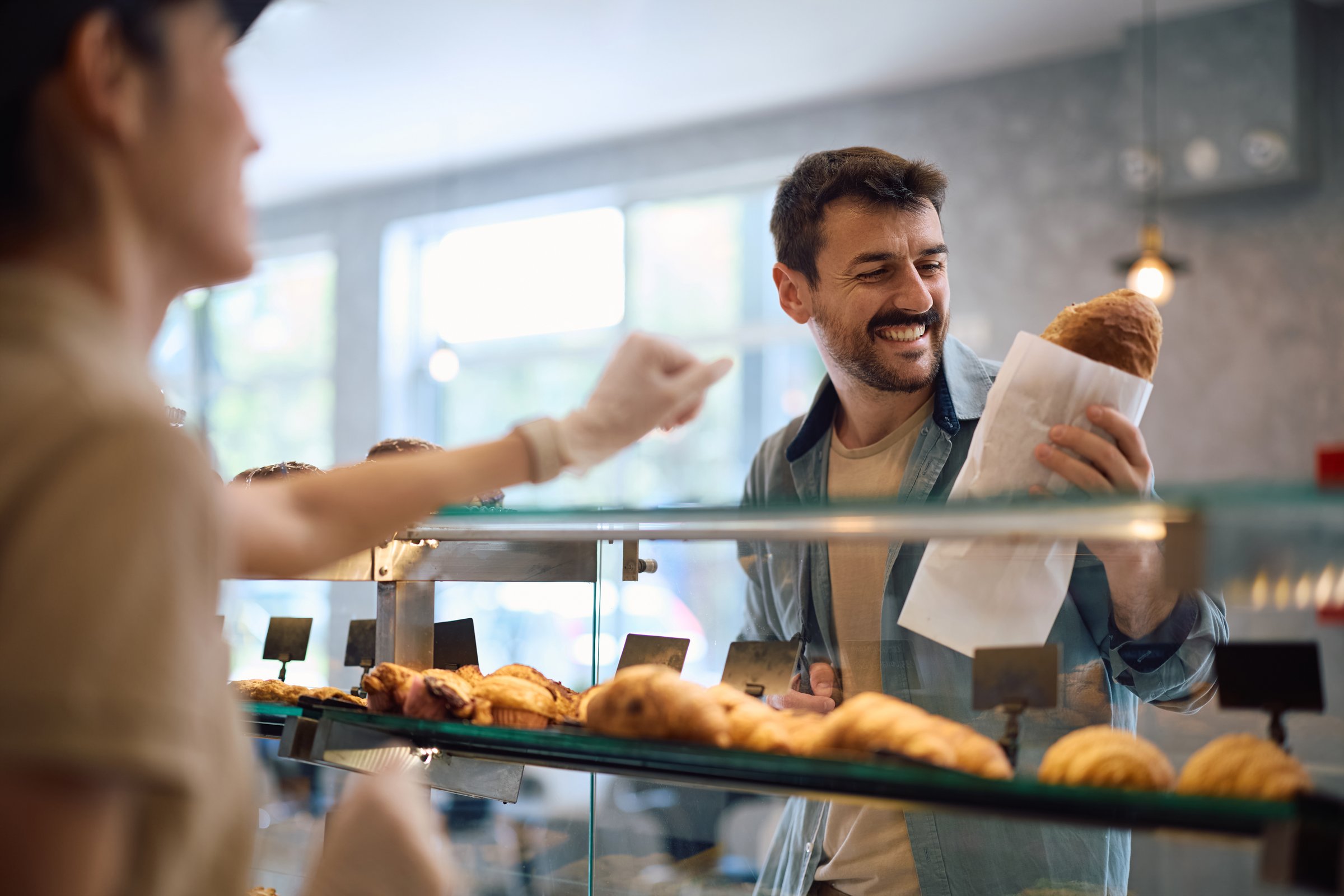 Happy bakery customer buying loaf of bread.
