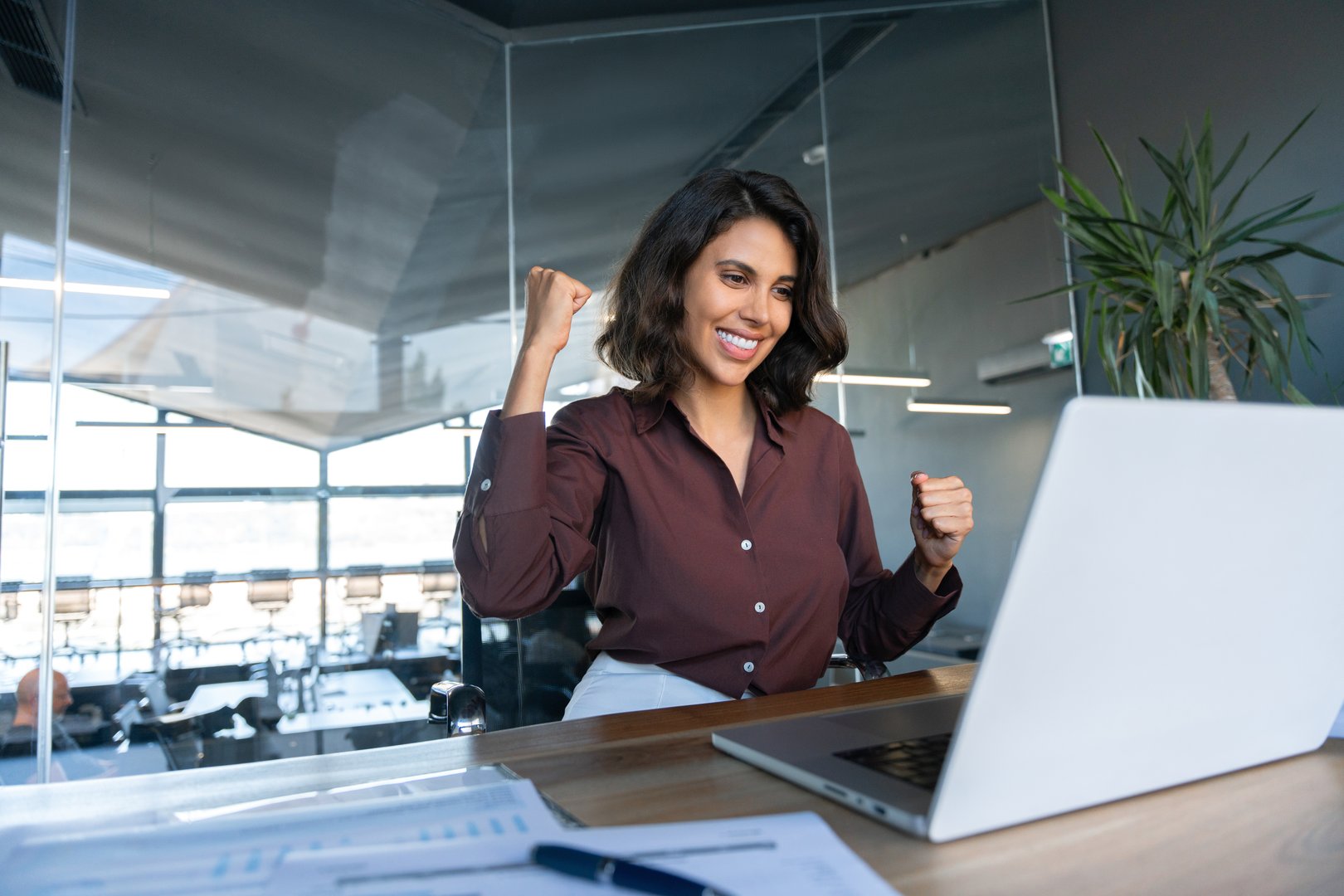 Happy excited young businesswoman looking at laptop pc computer screen doing yes triumph win gesture. Smiling latin hispanic business woman successful winner celebrating winning in office. Copy space