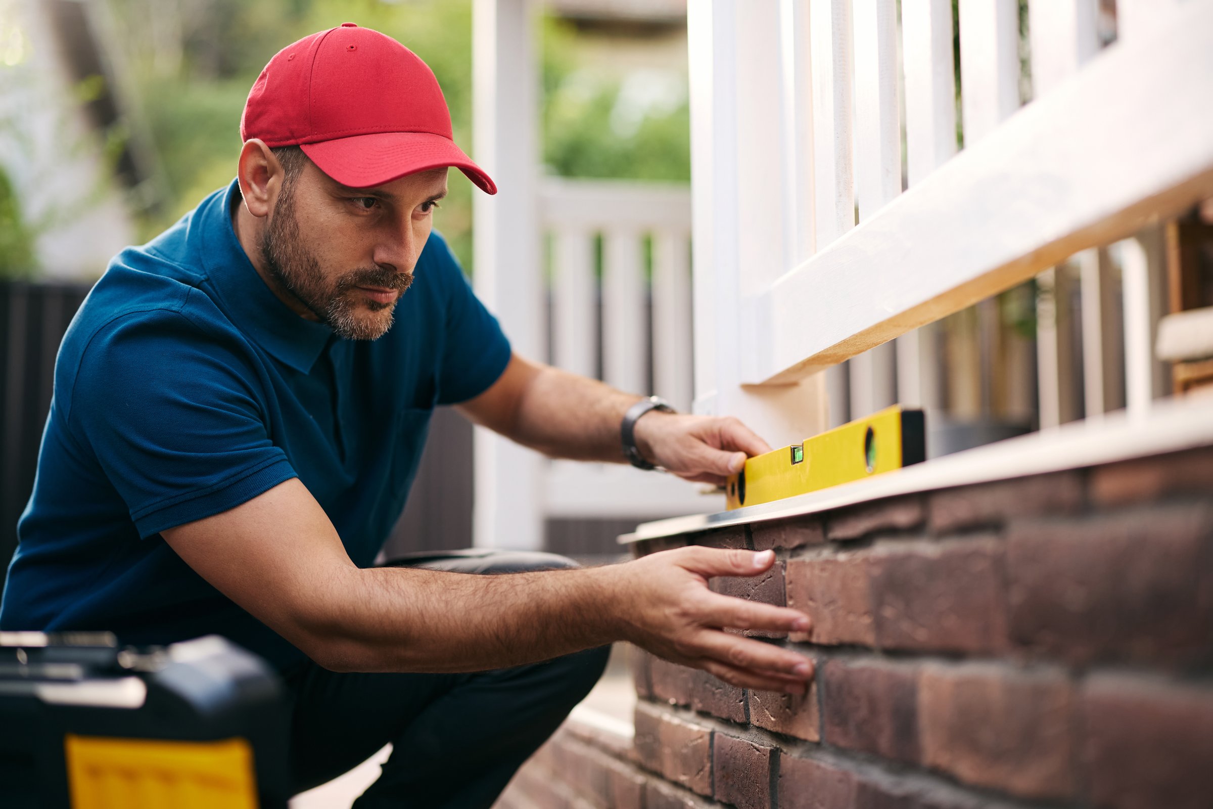 Construction worker using level while repairing a porch wall.  Copy space.