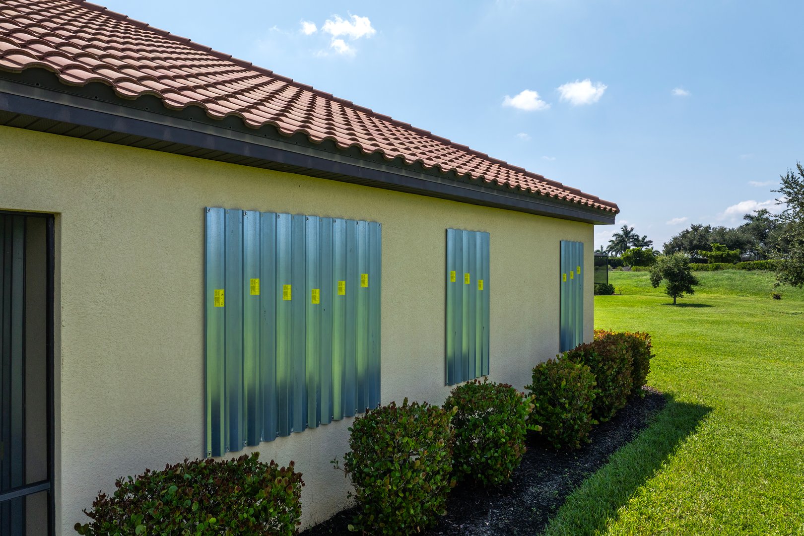 Boarded up windows with steel storm shutters for hurricane protection of residential house. Protective measures before natural disaster in Florida.