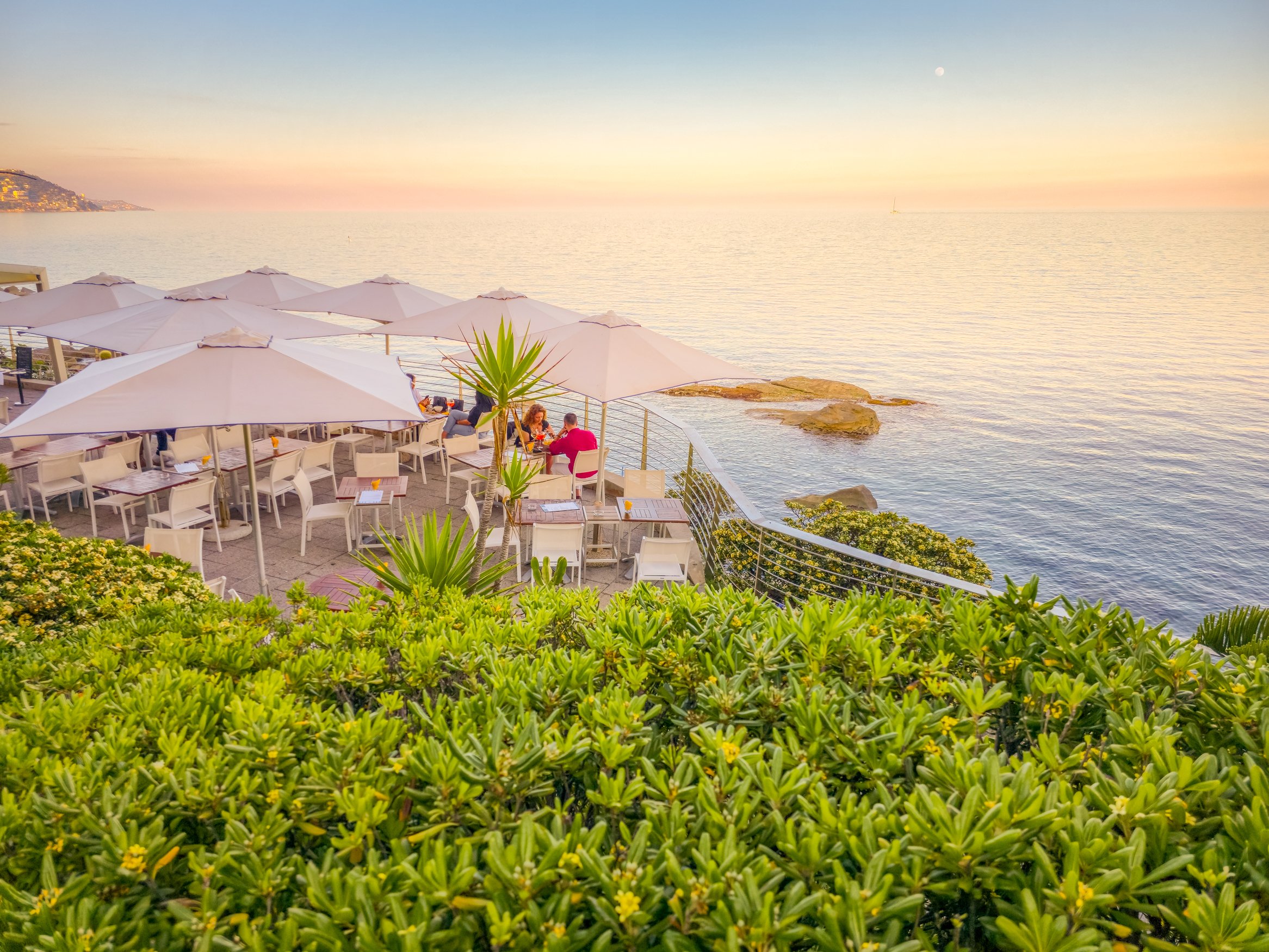 Bordighera, Italy - 10 May, 2025: People enjoying the sunset in a beach. The graceful seaside resort has elegance and Mediterranean charm blend with a relaxed atmosphere.