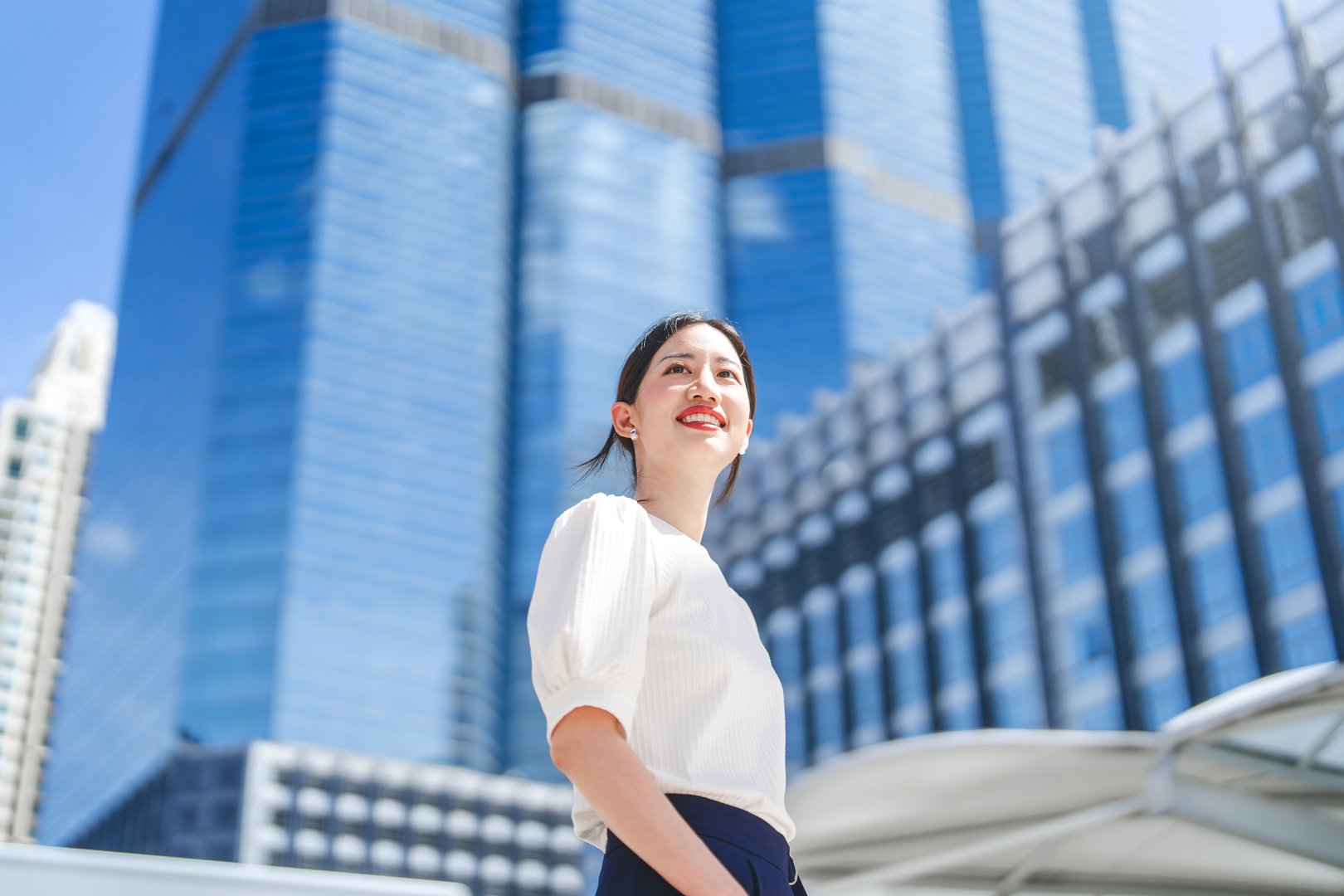 Portrait of business asian woman. Entrepreneur standing at outdoors sunny day city building background. Successful goal looking forward. Positive beautiful smiling.