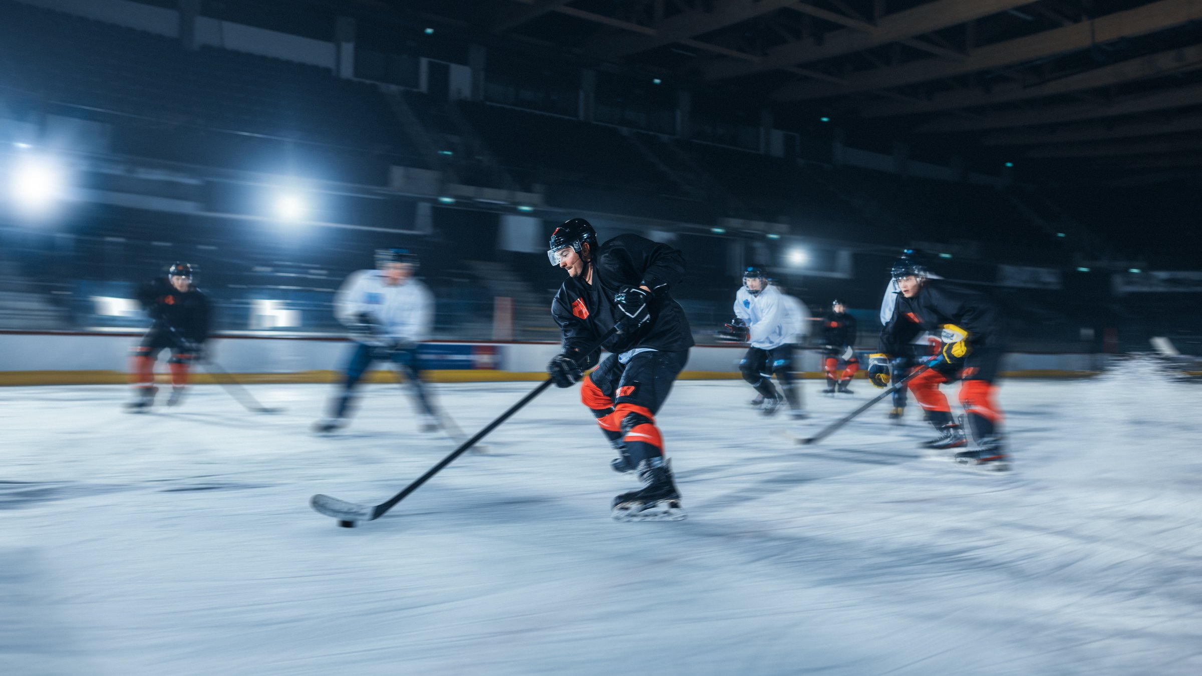Ice Hockey Rink Arena: Professional Forward Player Breaks Defense, Hitting Puck with Stick to Score a Goal. Blurred Motion Shot.