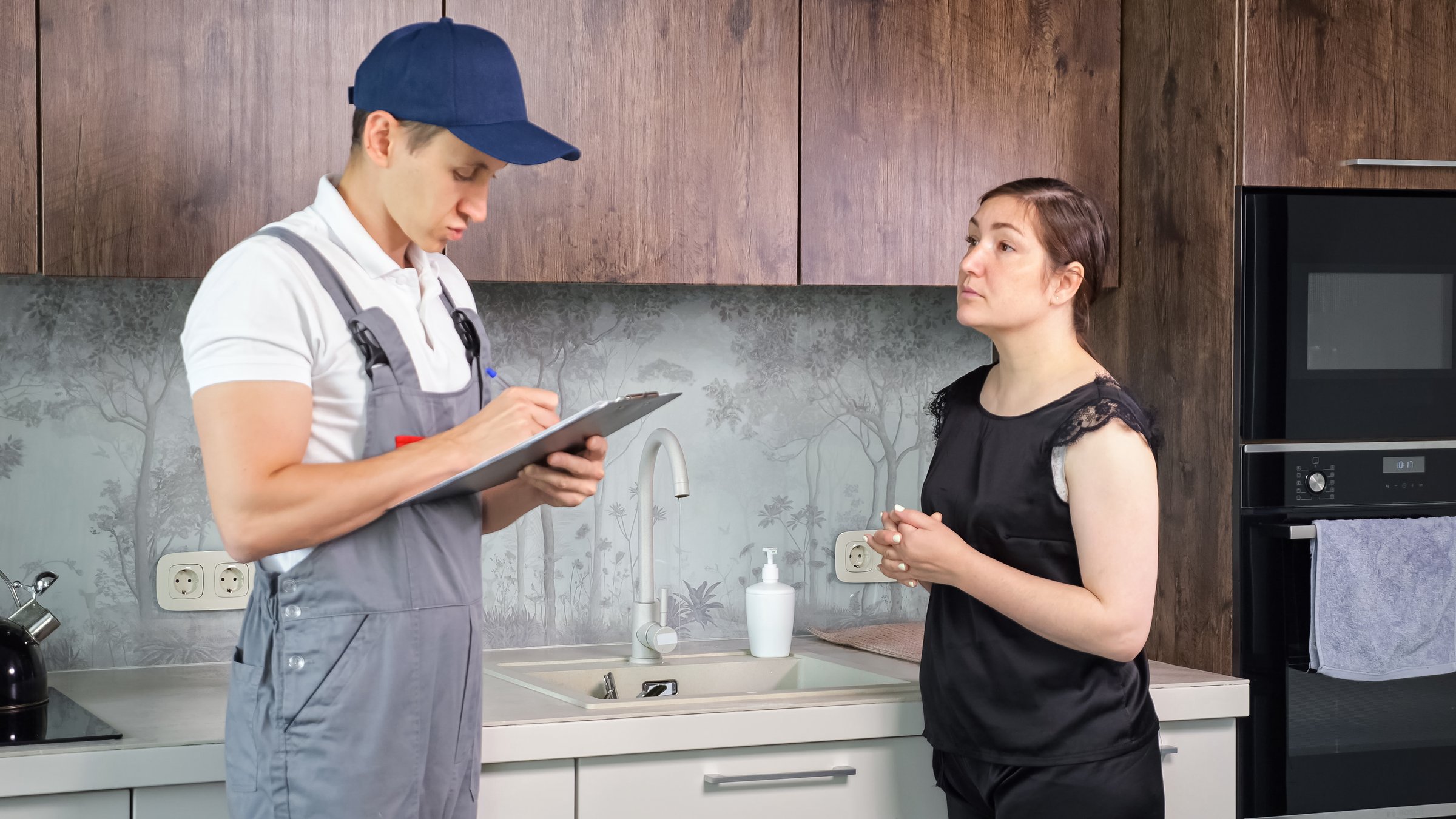 Female owner of apartment thanks plumber for repaired faucet in kitchen premise. Plumbing service. Emotional conversation between woman and man