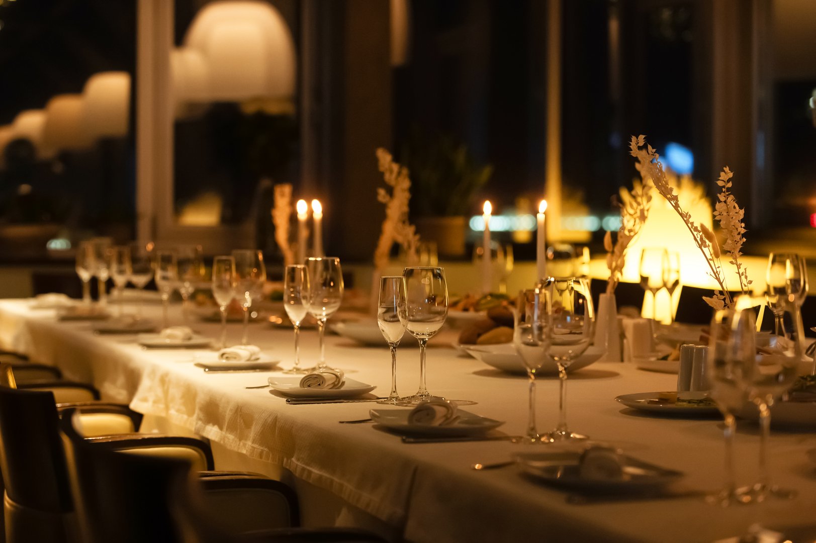 A beautifully arranged dining table is set with glasses and candles, creating a warm atmosphere for guests.