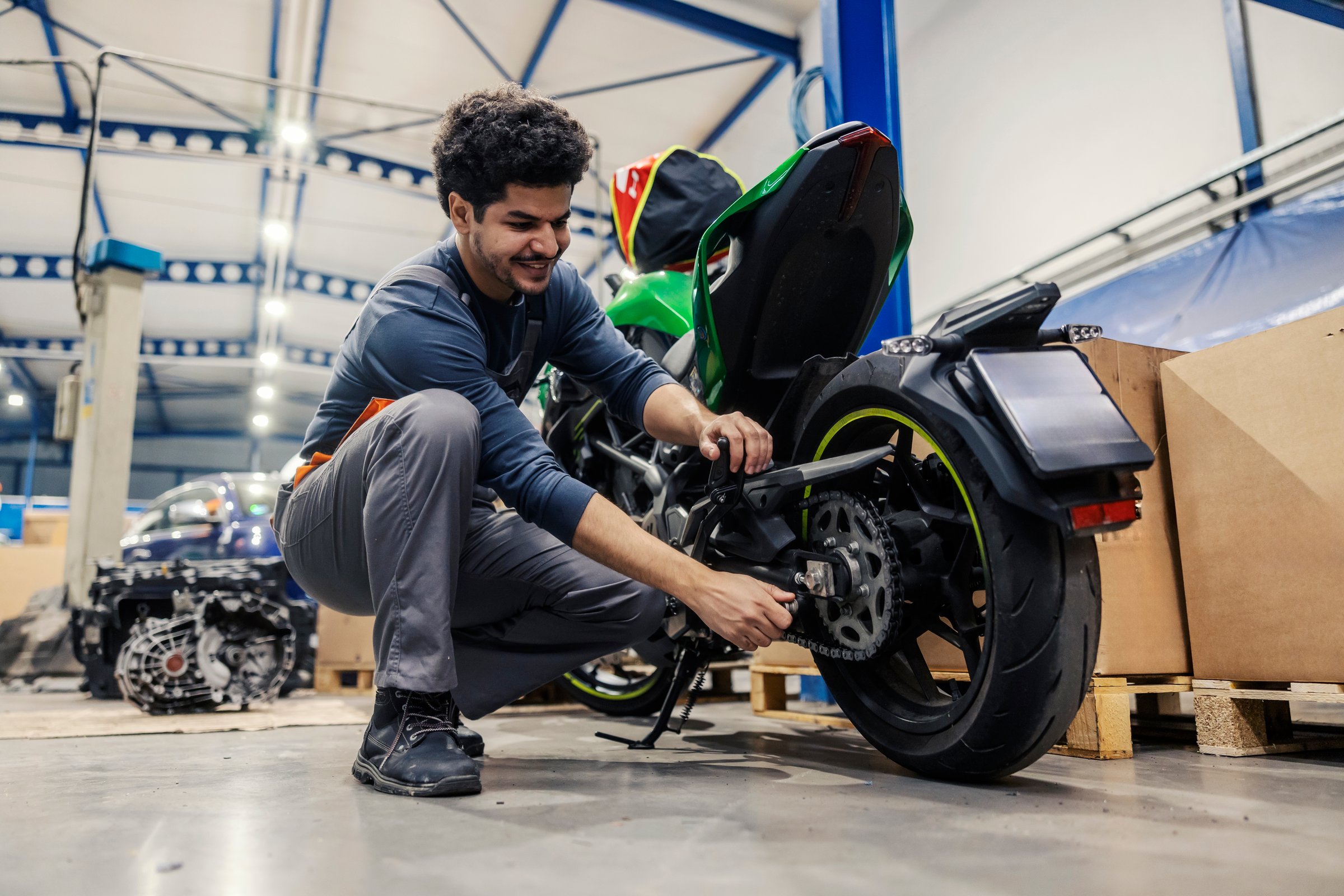 Happy interracial technician repairing motor bike at auto mechanic shop.