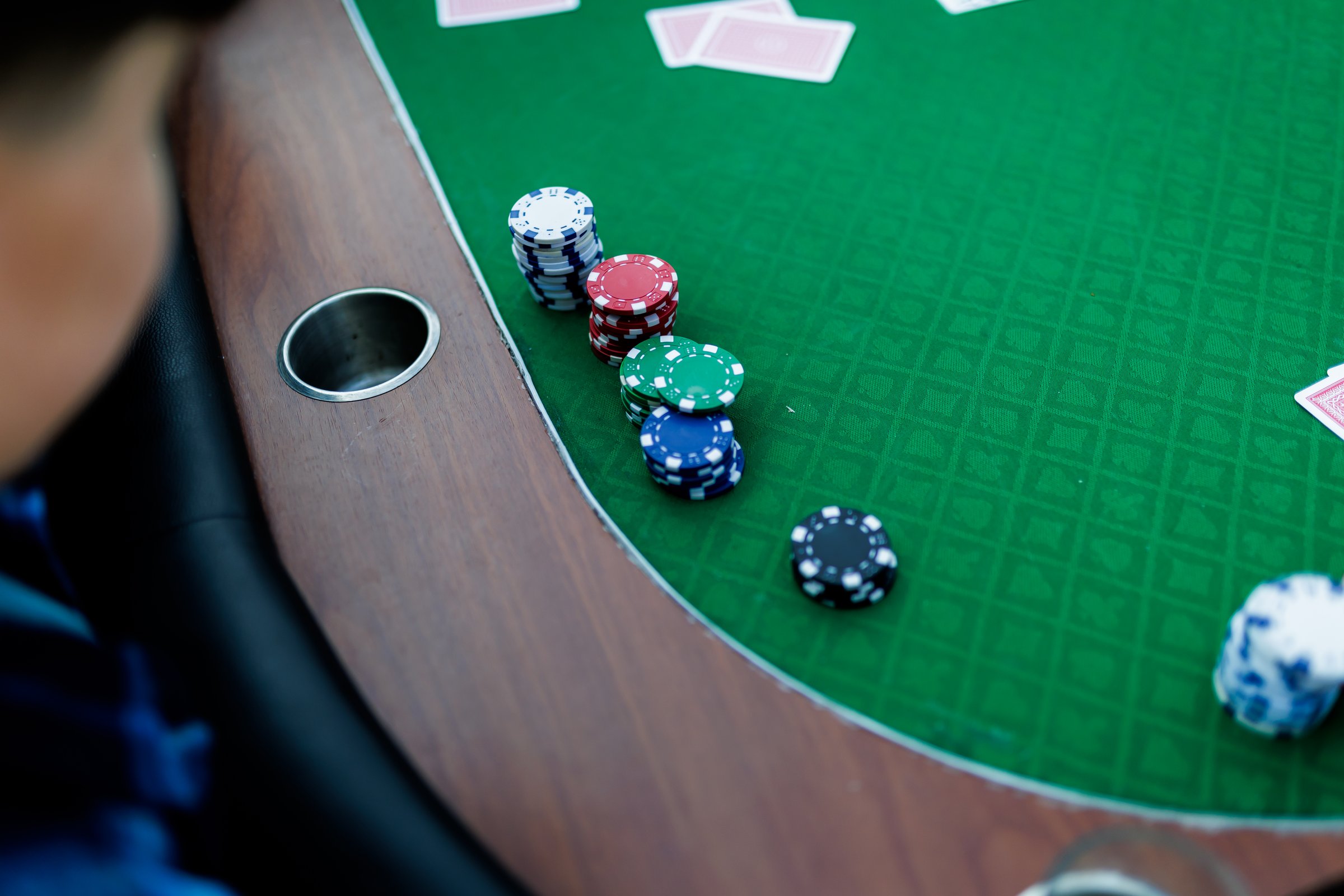 Detailed shot of hands shuffling poker chips and holding playing cards during a high-stakes game. The vibrant colors of the chips and the crisp textures of the cards emphasize the energy and tension of the moment