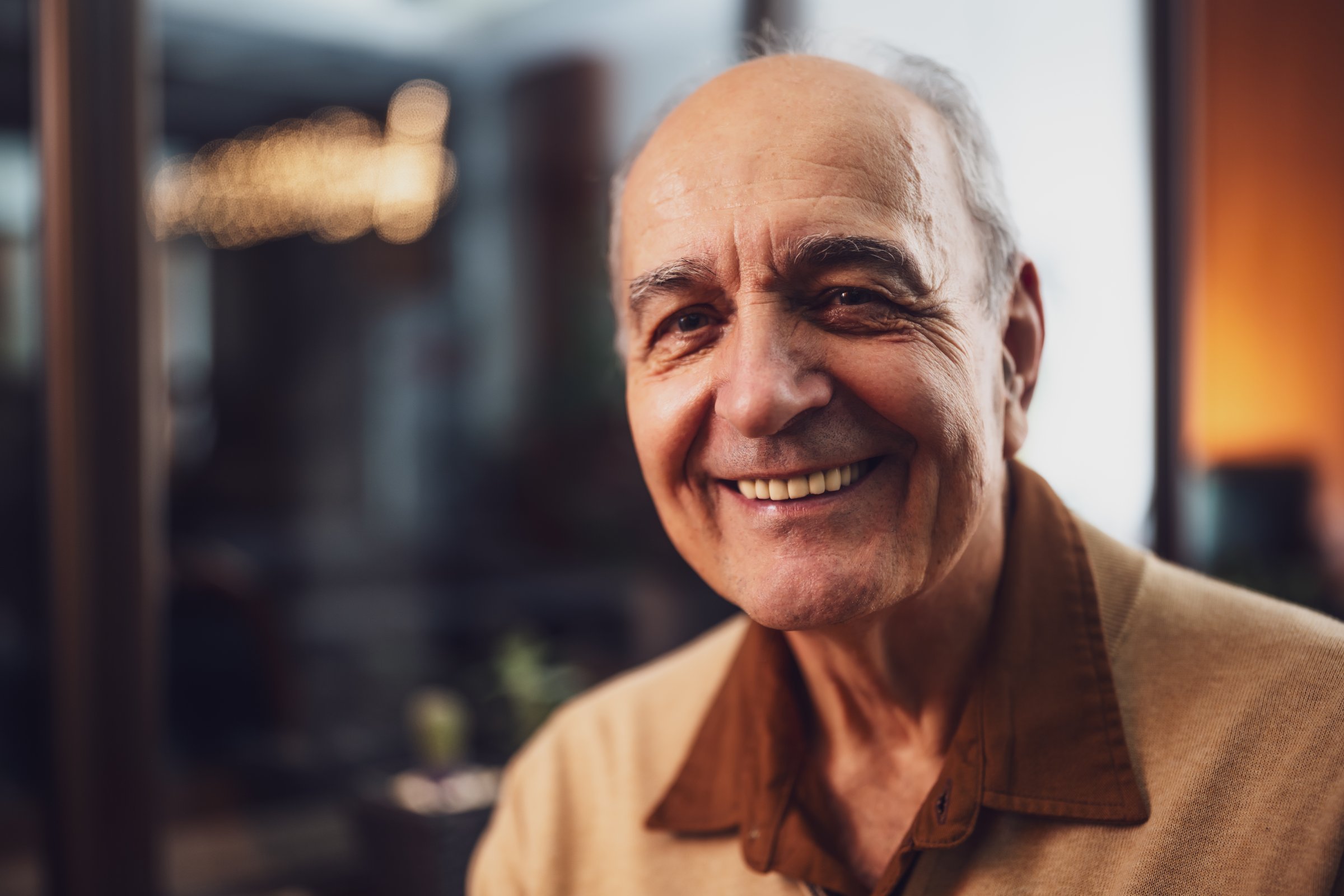 Close up portrait of happy senior smiling and looking at camera while sitting in the cafe at evening.