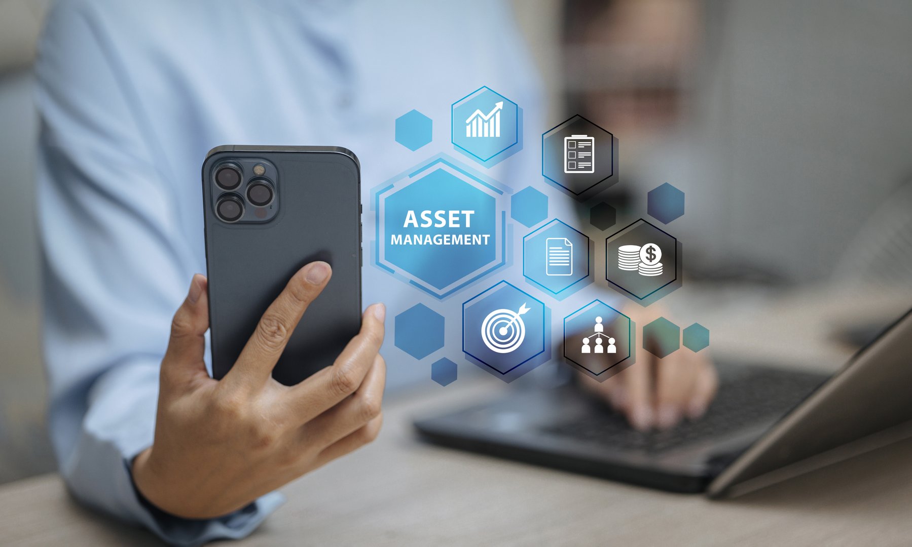 Person using smartphone with digital asset management icons and laptop. Concept of business finance, investment, fintech, technology solution, and corporate resource management.