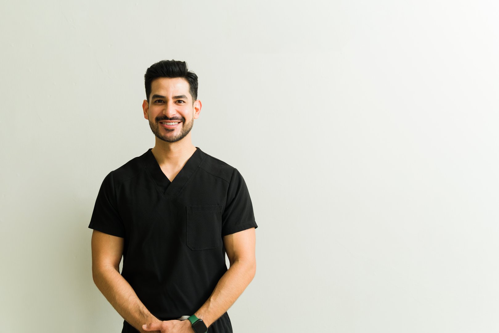 Male therapist smiling confidently during physical therapy treatment, providing rehabilitation care in professional medical setting