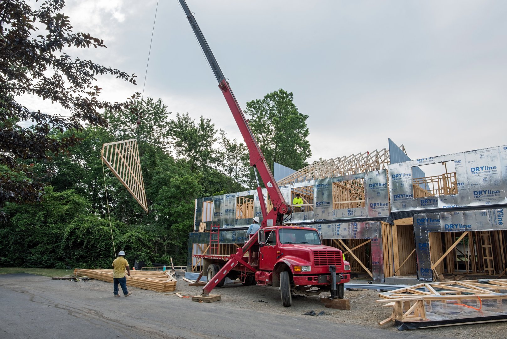 Dayton, Ohio - June 19, 2024: Mechanical crane is lifting and transporting roof rafter into place at construction site of new condo housing development.