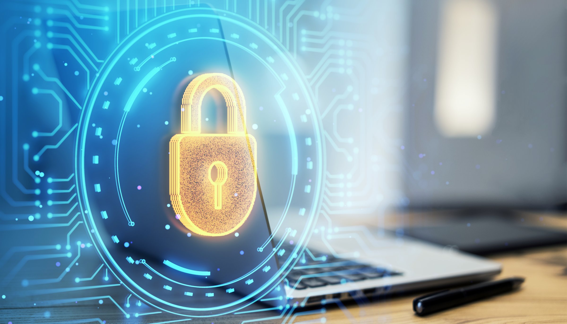 Digital padlock hologram overlaying a laptop on a desk, with a blue circuit background. Concept of cybersecurity and data protection