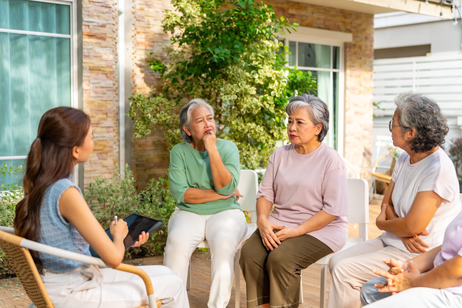 Group of Asian senior mature woman talking discussion about mental health and life problem thoughtful with professional psychiatrist in the garden. Elderly people mental health care and therapy concept.