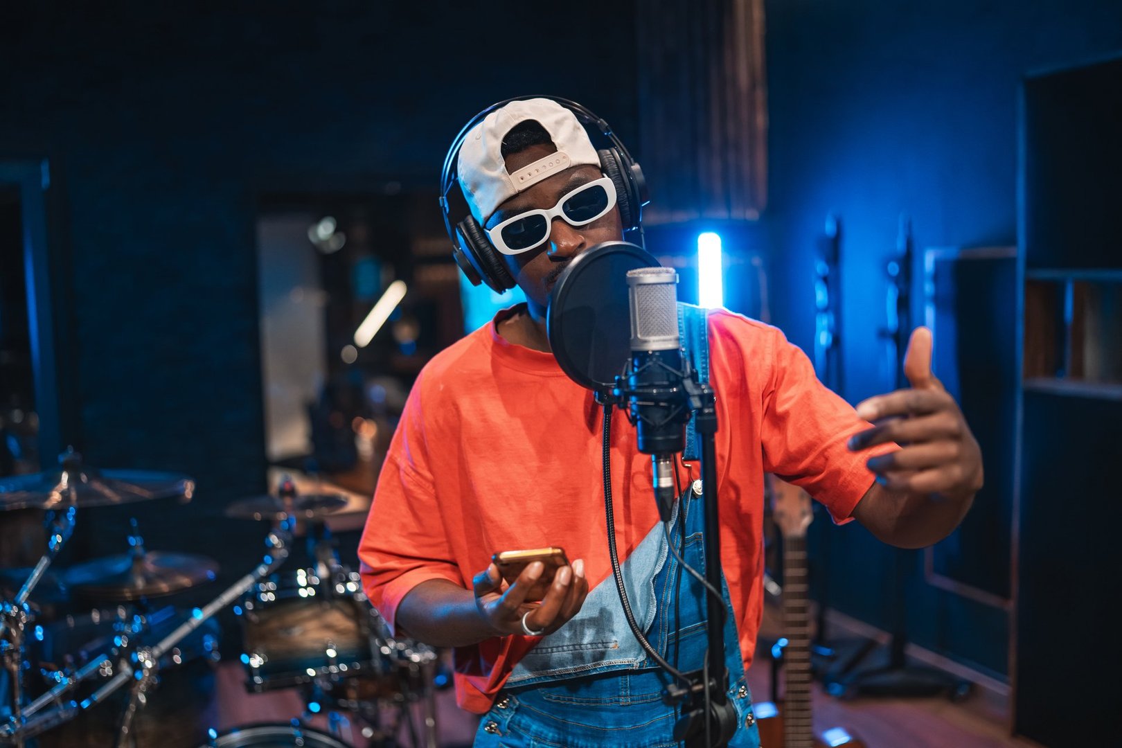 Young african american musician is recording a song in a professional recording studio, using a microphone and headphones