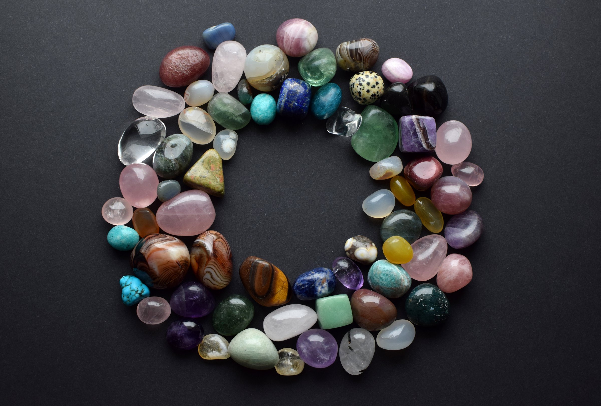 Natural stones of different colors are laid out in a circle. Predictions, witchcraft, spiritual esoteric practice. Background of precious stones.