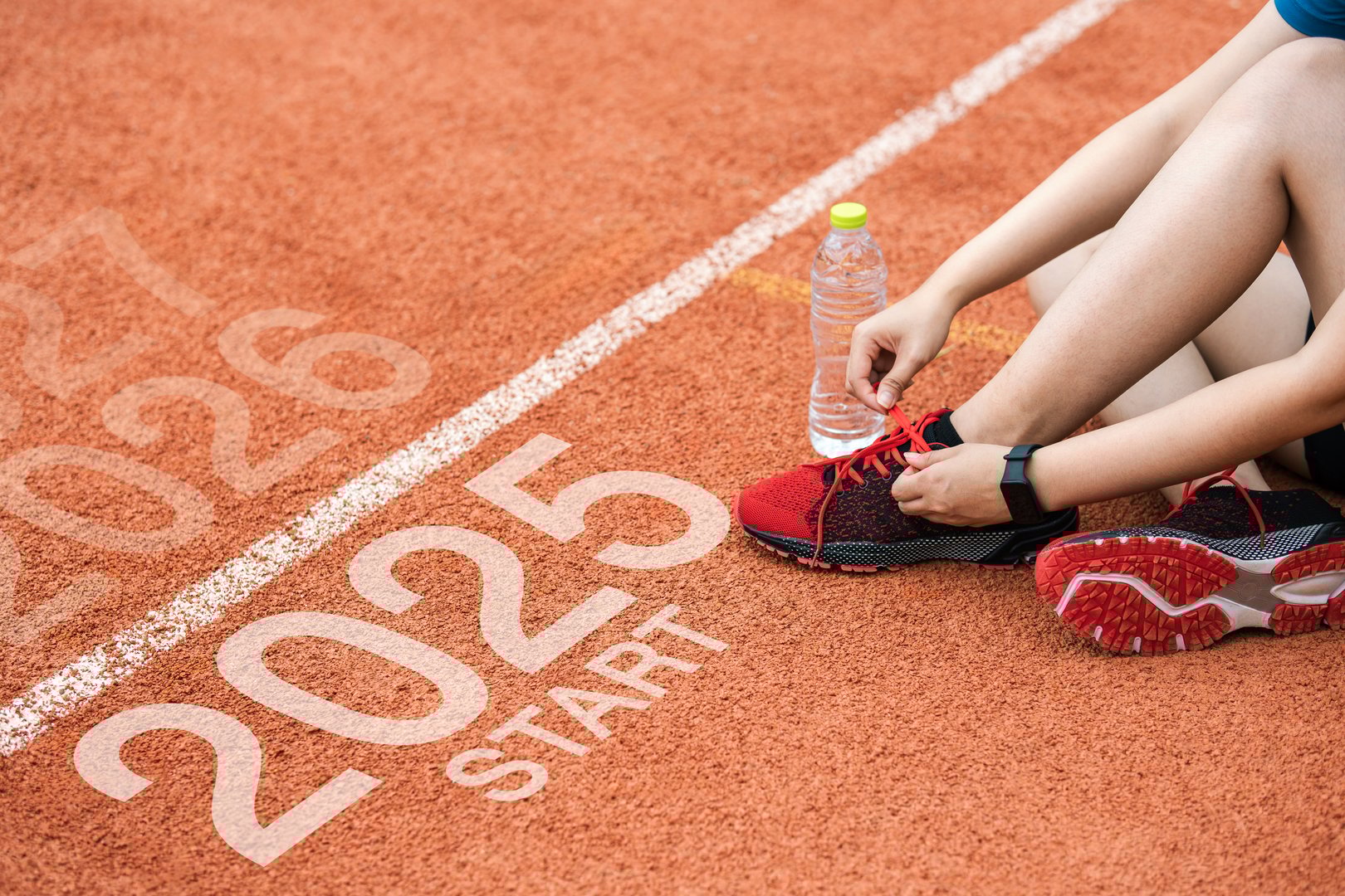 New year 2025 concept, beginning of success. Text 2025 written on asphalt road and male runner preparing for the new year. Concept of challenge or career path and change.