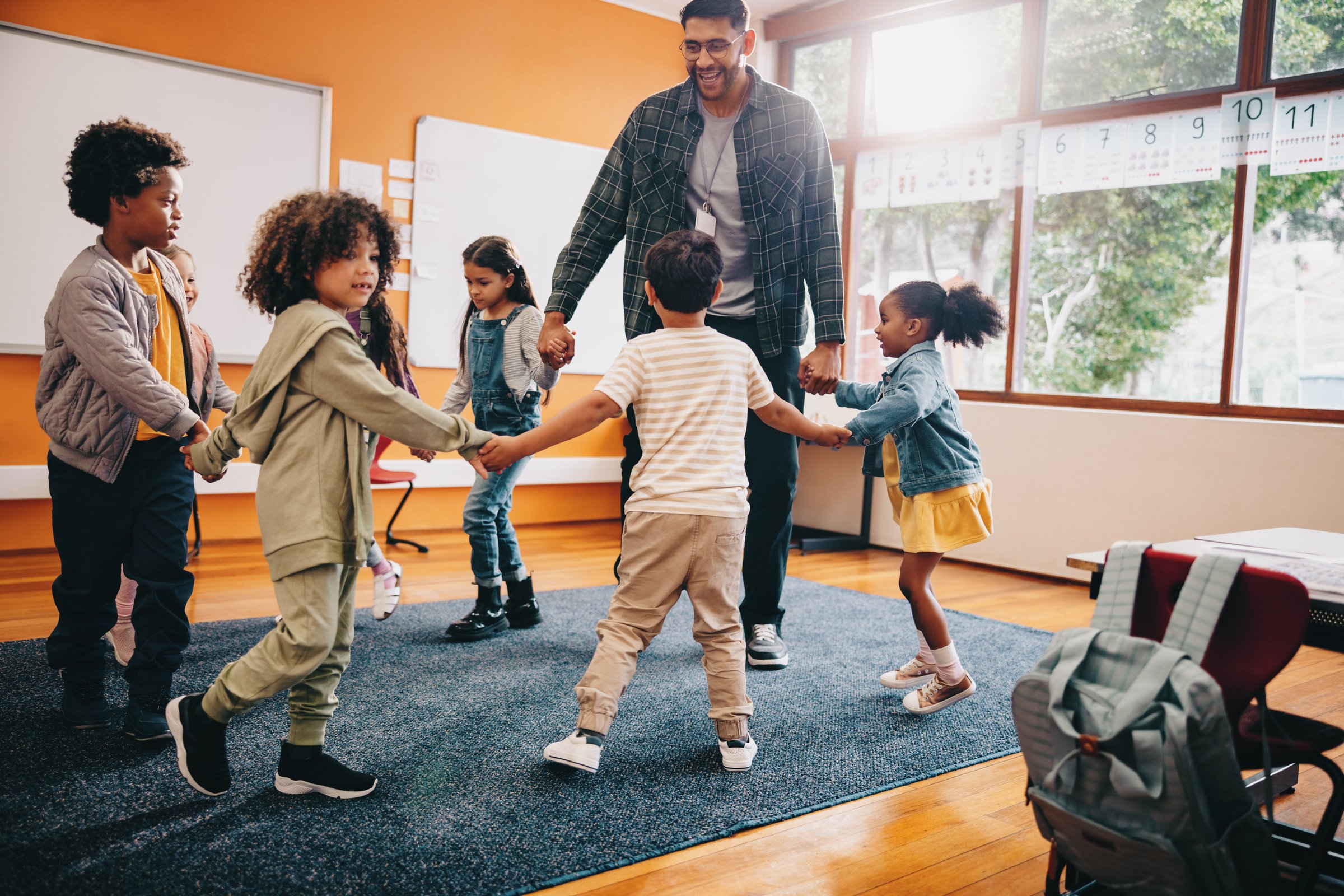 Elementary school fun. Teacher playing a game with his students in a classroom. Fun is a part of early child development.