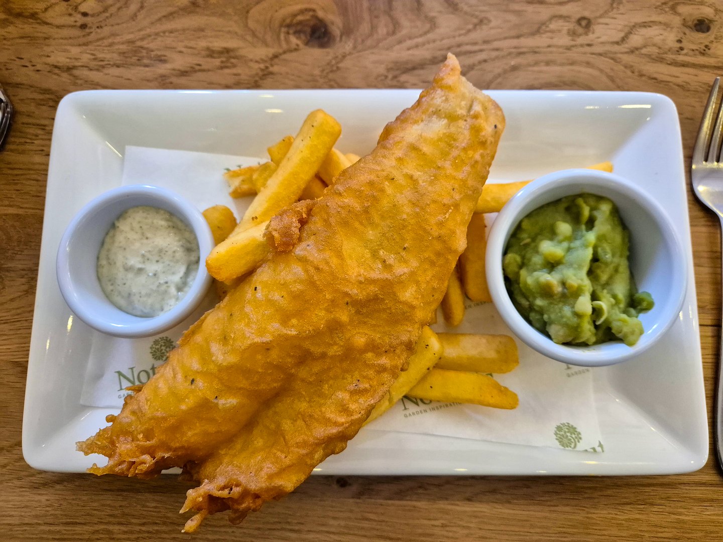 A delicious lunch of fish and chips with mushy peas and tartare sauce.