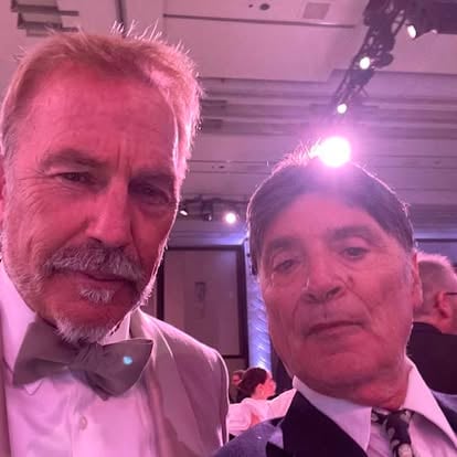 Two men in formal attire at an indoor event with soft lighting. One wears a bowtie, the other a necktie.