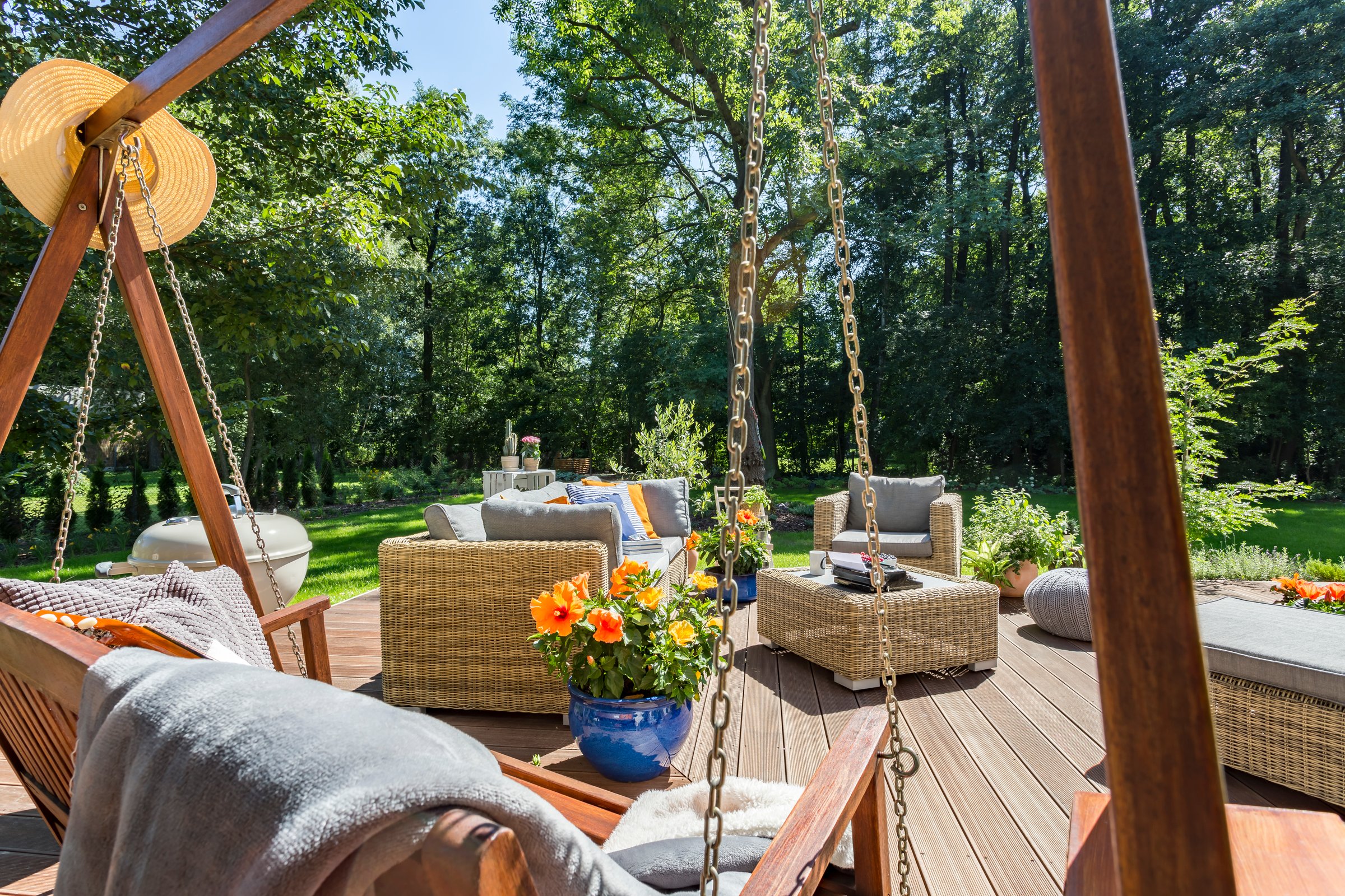 Comfortable house veranda with the wicker furniture and view of a garden in a summertime