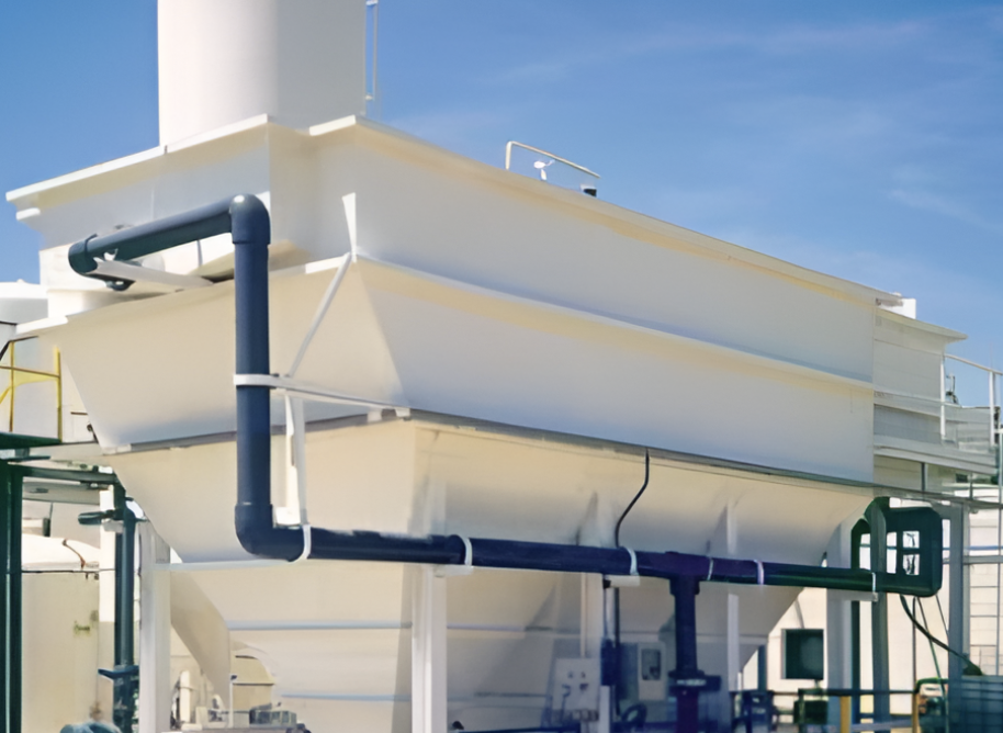 Large industrial water treatment equipment with pipes and tanks outdoors against a clear blue sky.