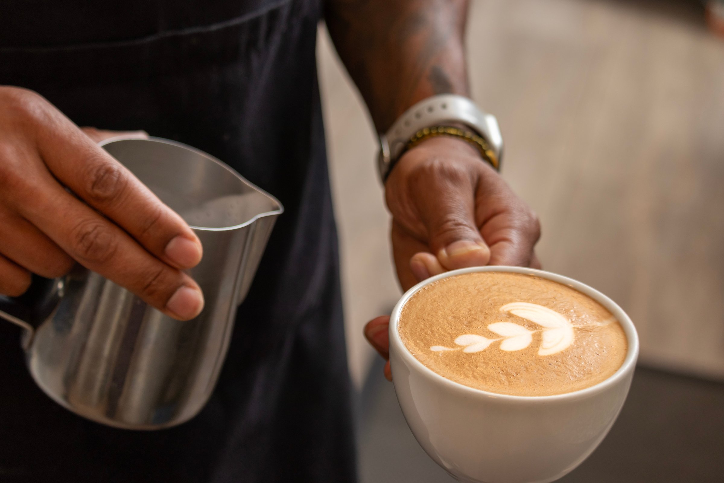 Barista pouring milk into coffee cup creating latte art