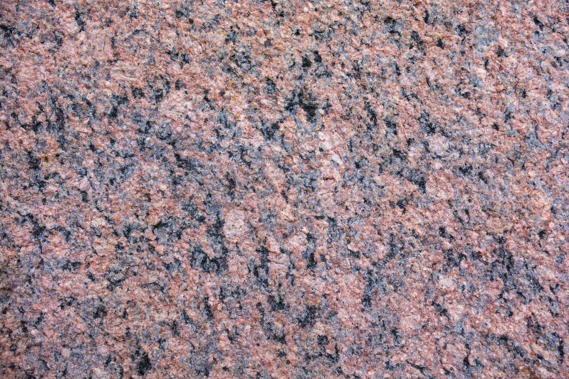 A close up of a stone wall with a greyish color. The wall is made of granite and has a rough texture