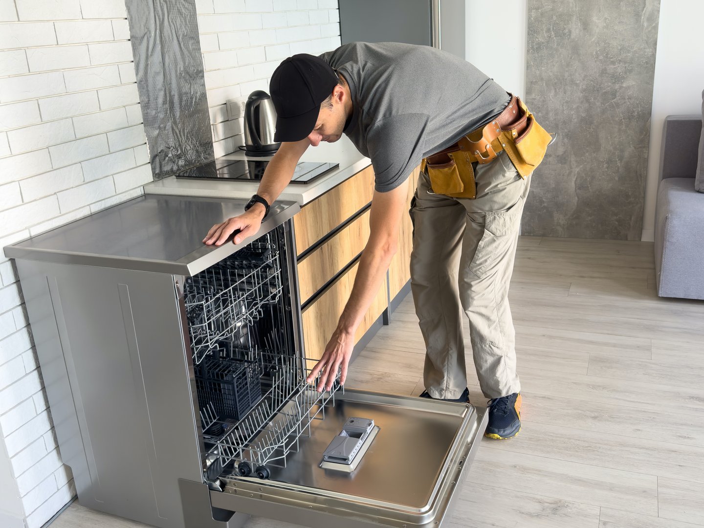 Young Repairman Service Worker Repairing Dishwasher Appliance In Kitchen. High quality photo