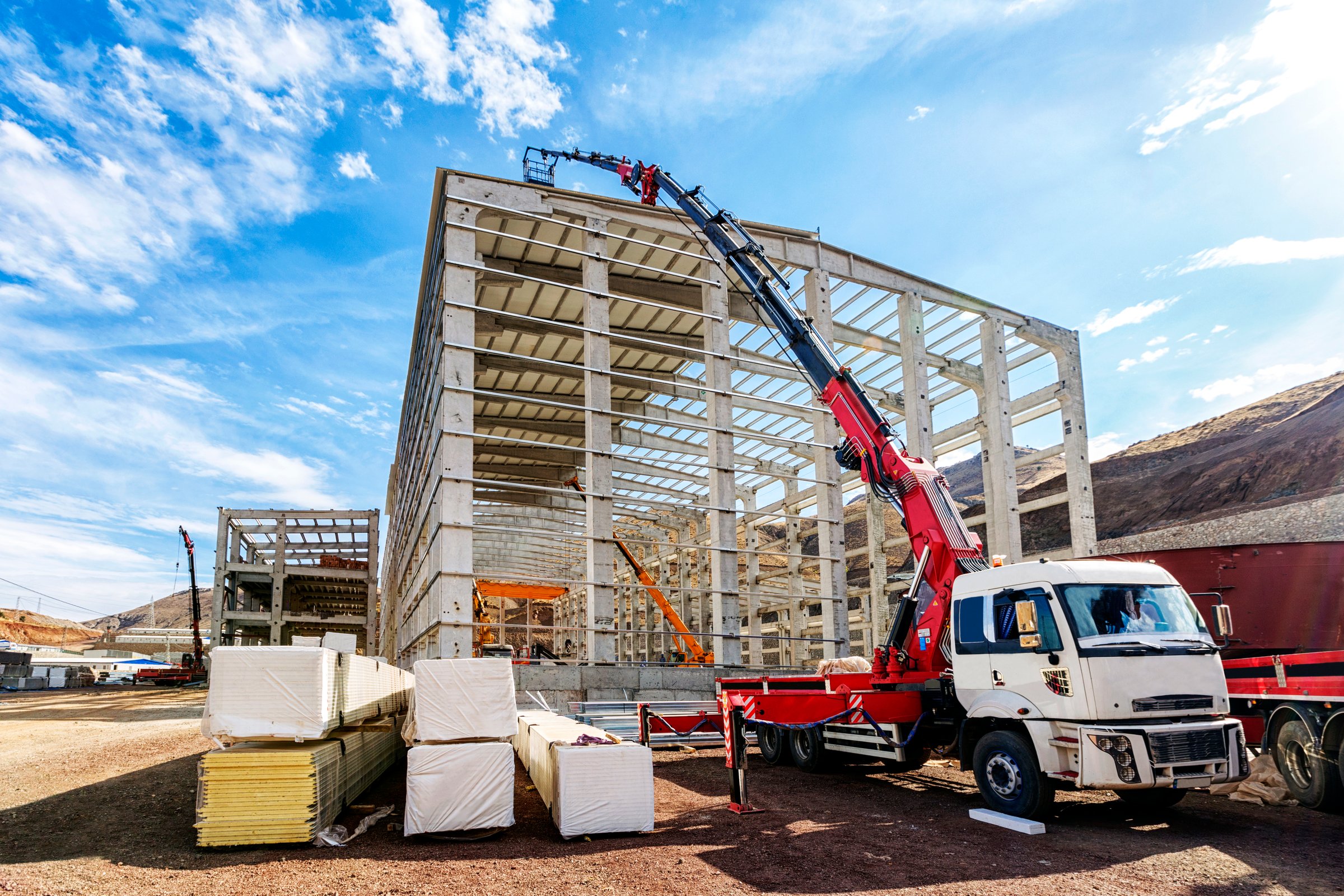 The crane ( HIAB ) extend its lift bucket to roof of the new building for isolation in the construction site. HIAB is a Swedish manufacturer of loader cranes, demountable container handlers, forestry cranes, truck-mounted forklifts and tail lifts.