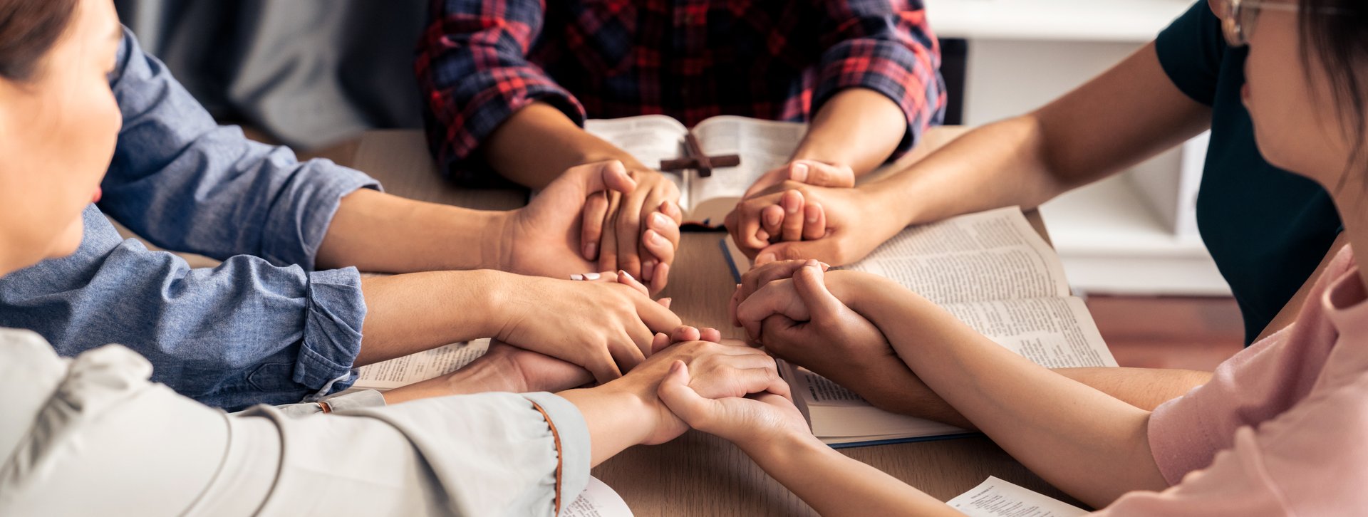 Cropped image of diversity people hand praying together at wooden church on bible book while hold hand together with believe. Concept of hope, religion, faith, god blessing concept. Burgeoning.