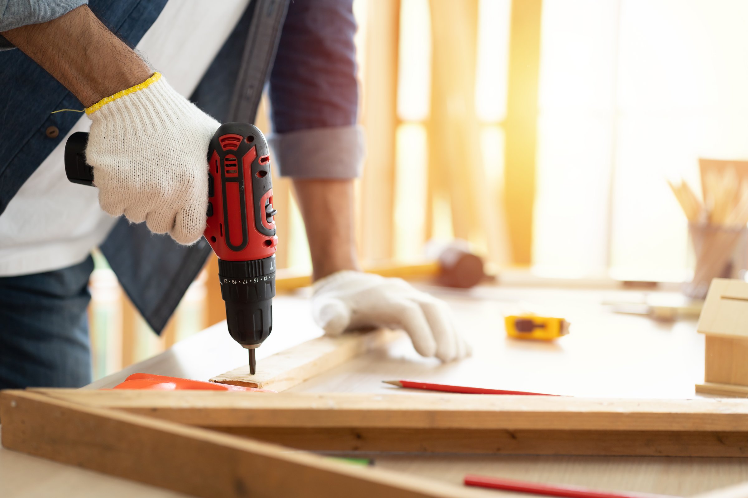 Hands of carpenter uses hand drill to assemble the wood in the carpentry shop