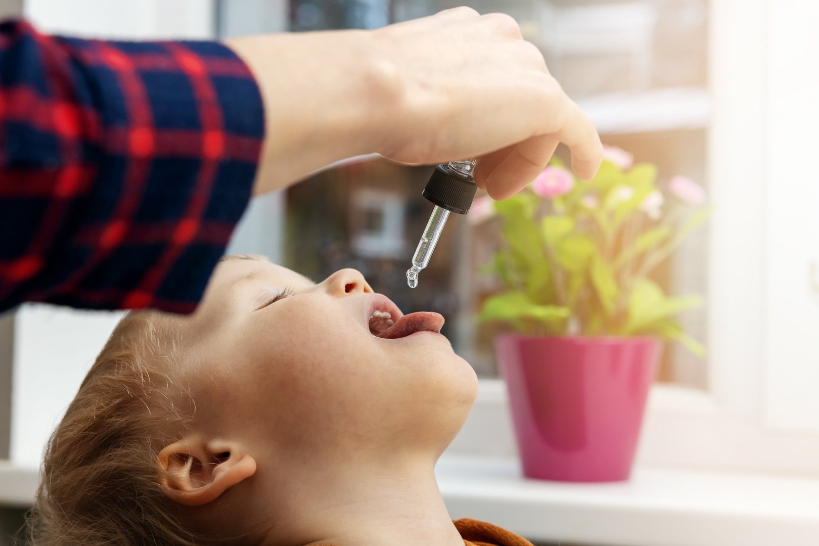 mother giving vitamin drops with dropper to her child. dietary supplements for kids