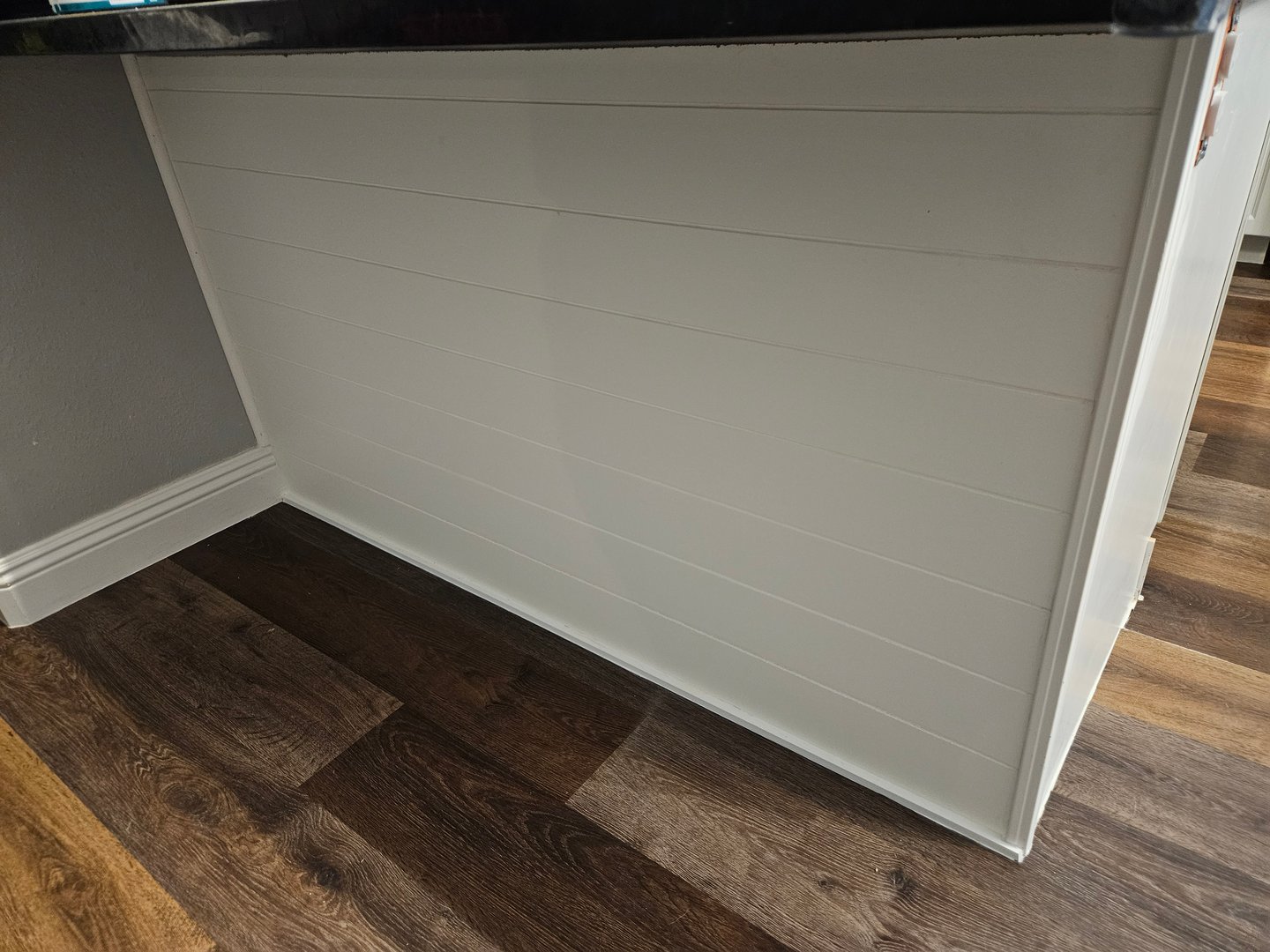 Vertical shiplap paneling installed on kitchen peninsula back panel