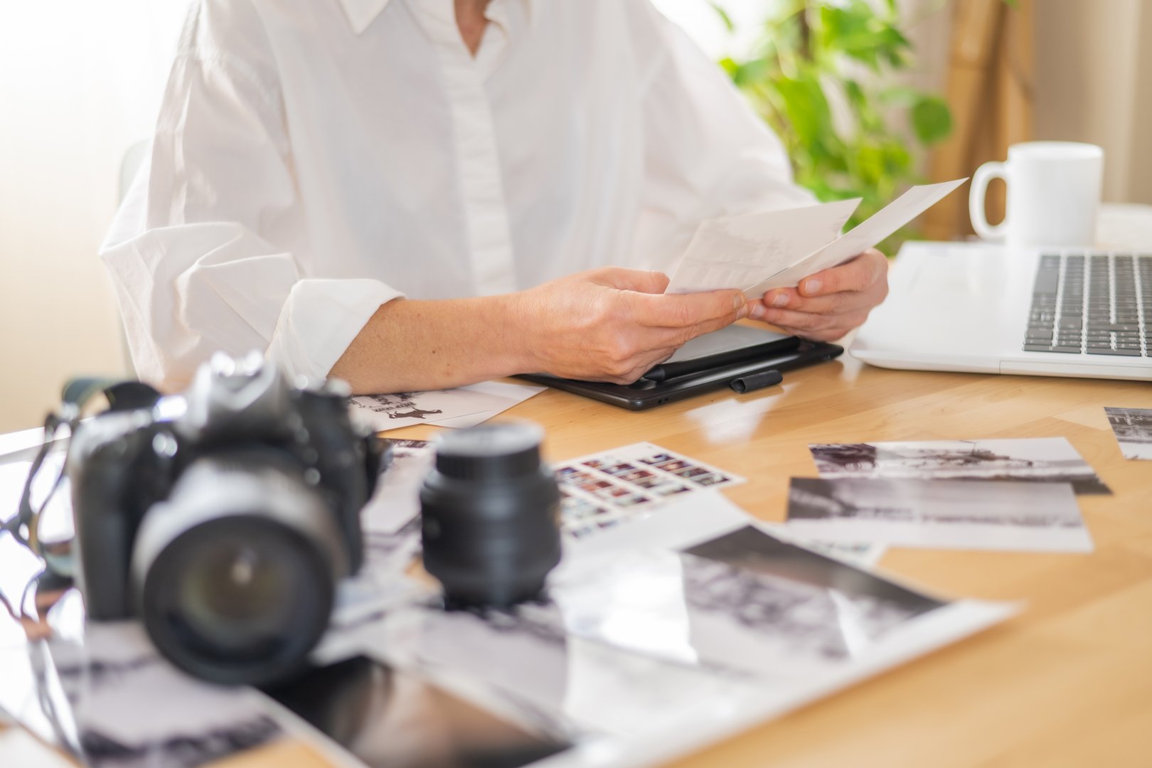 Photographer Working On Portfolio With Prints And Camera Equipment In Creative Studio