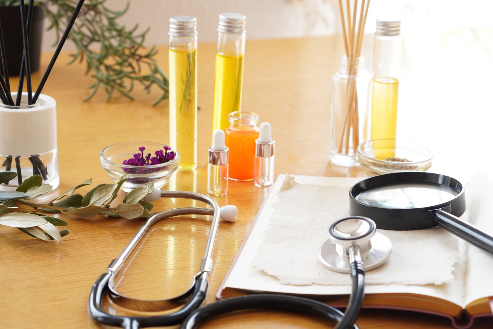 table of homeopathy, natural remedies, with plants and oils, stethoscope and open book