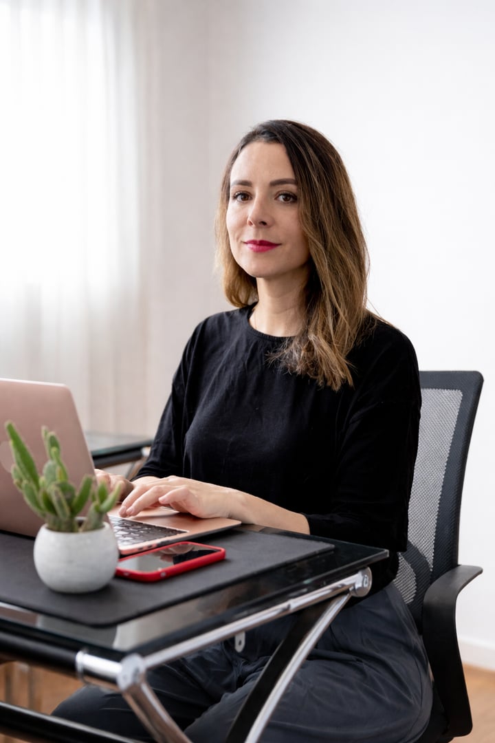 Portrait of female leader standing at corporate firm with arms crossed and smiling at camera.