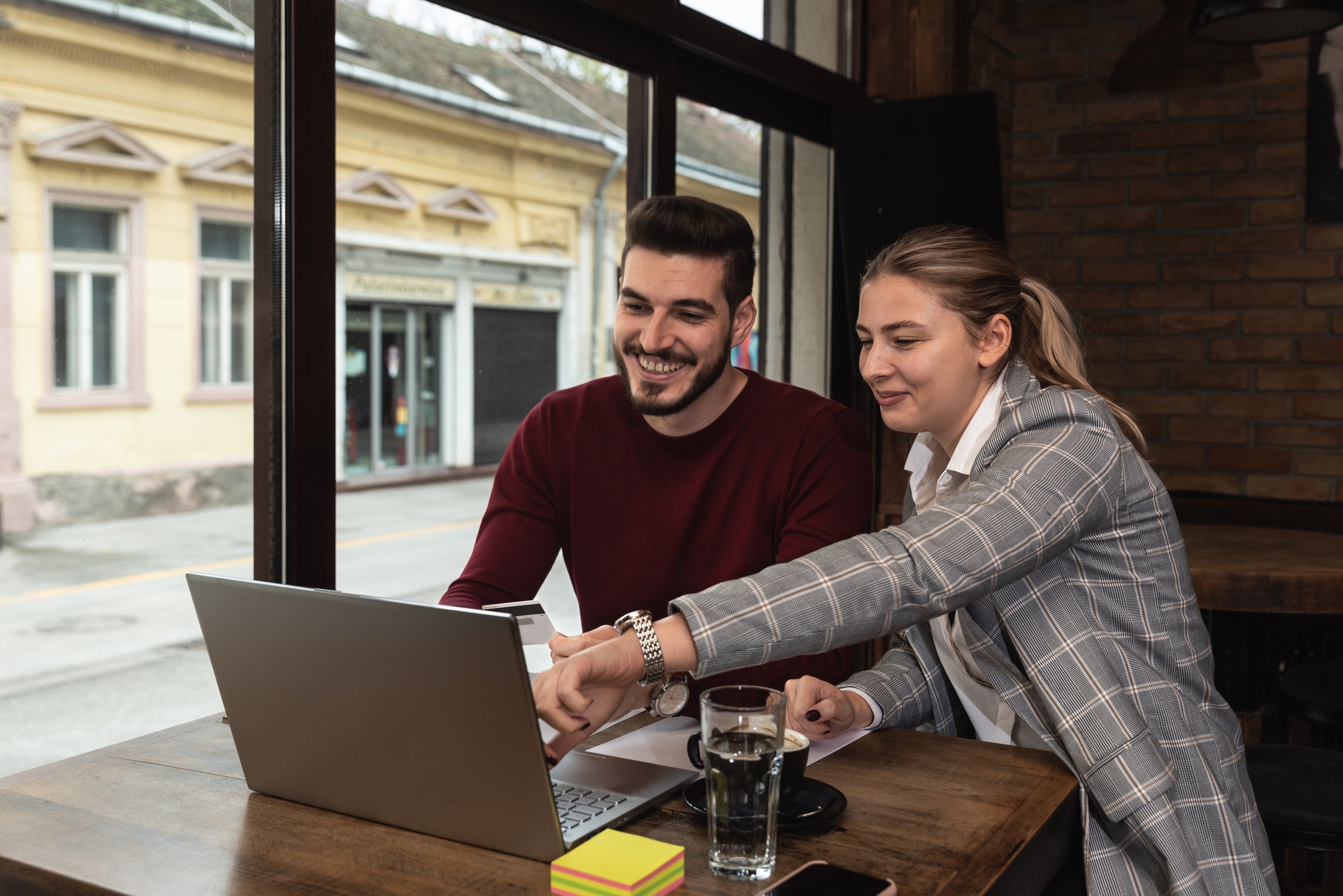 Smiling Caucasian Young barista couple love or partnership is wearing apron and consulting for marketing planning idea with tablet in the coffee shop. Start up for small cafe business owner concept.