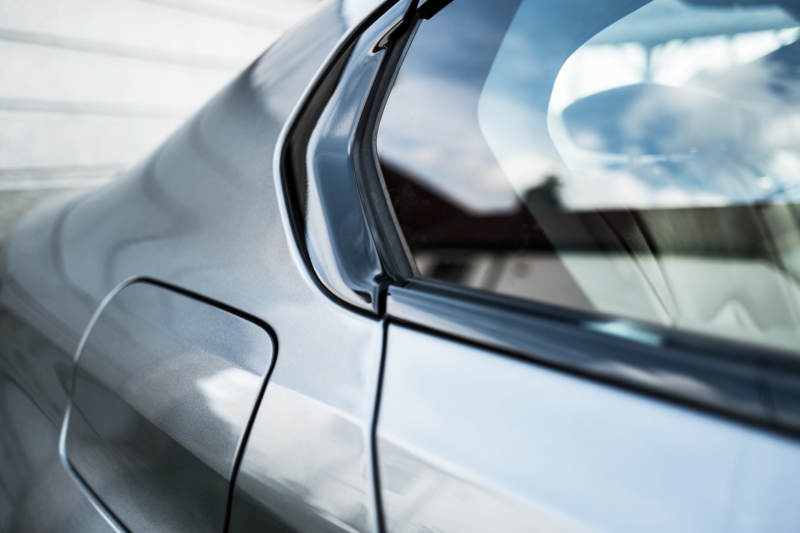 Shallow focus of the rear window and window edge seen on a German built luxury car. The deep lustre of the metallic paint can be seen.