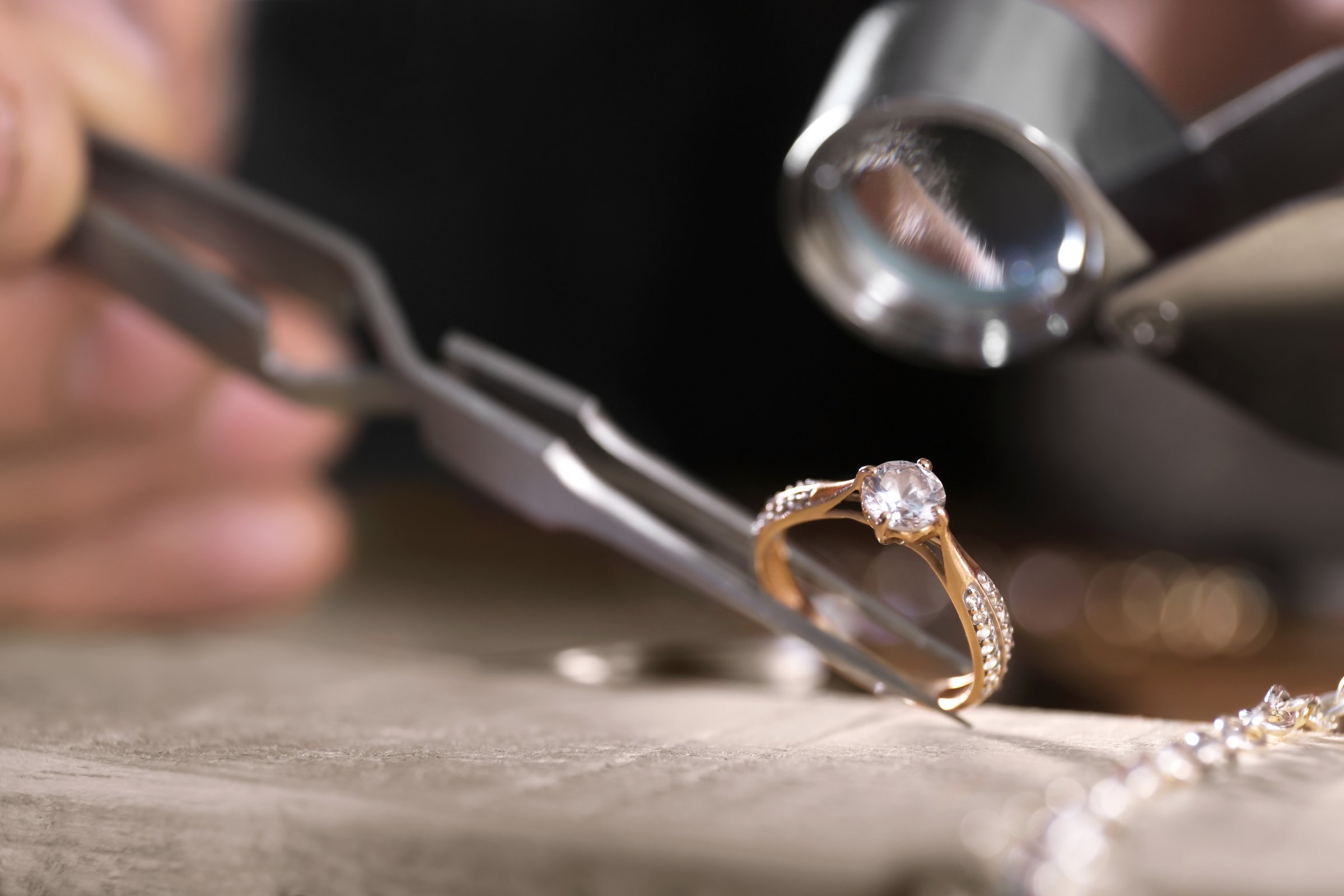 Jeweler Inspecting a Diamond Ring with Tweezers and Loupe.